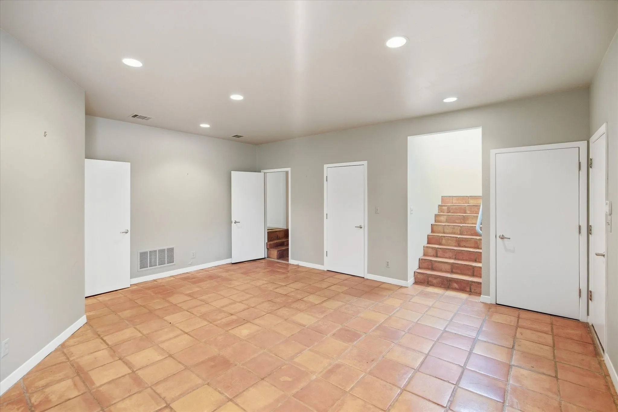 Spacious room featuring terra cotta tile flooring, recessed lighting, and multiple entryways