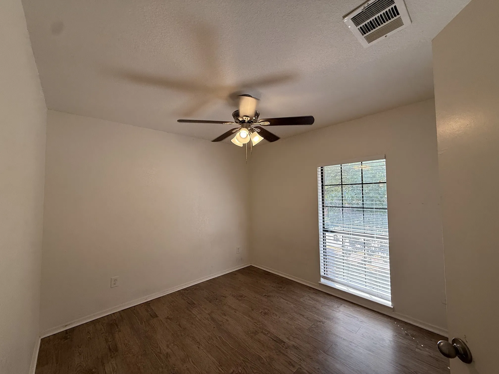 Wood-finish flooring, ceiling fan with integrated lighting, and window with horizontal blinds