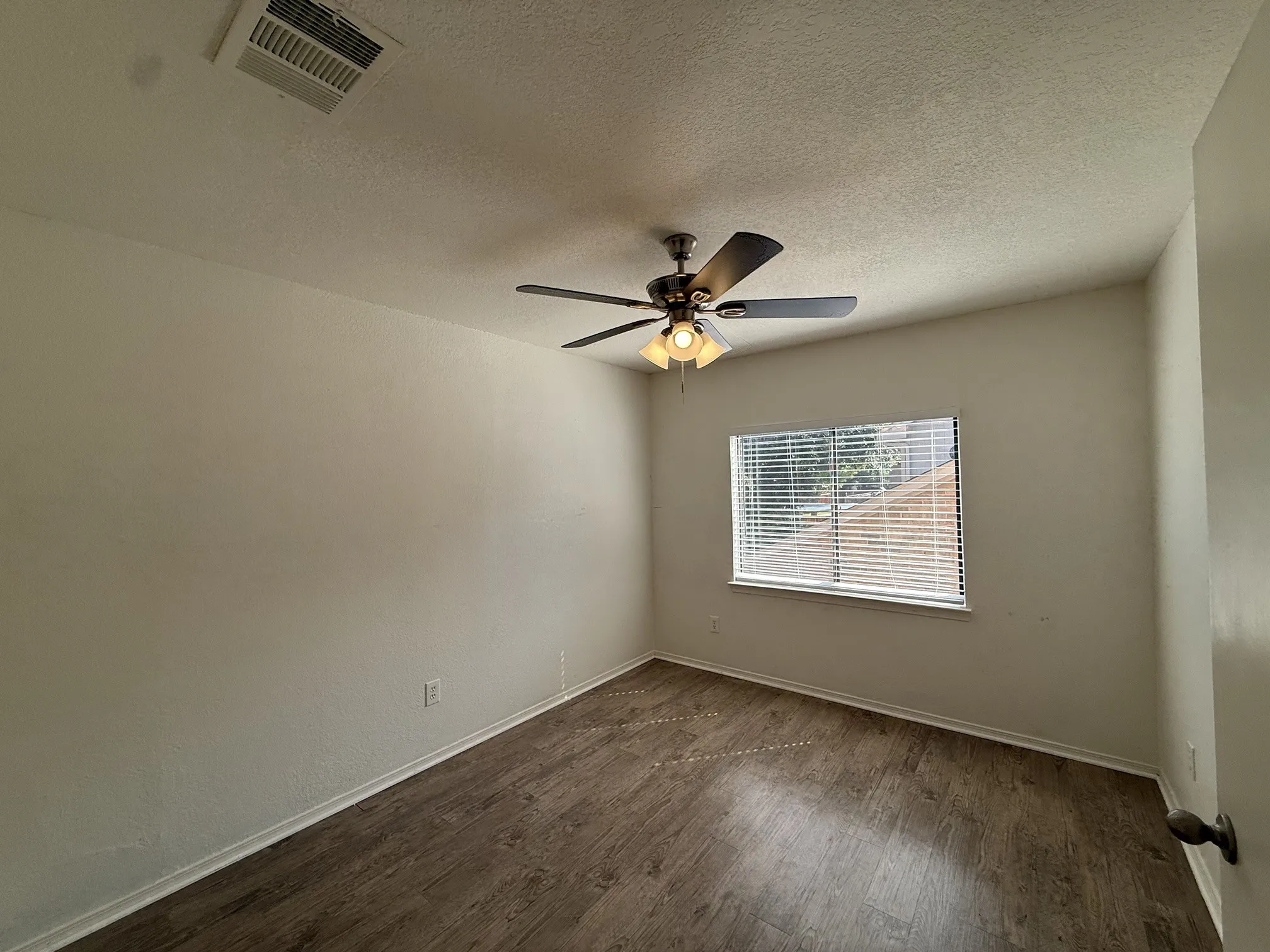 Wood-finish flooring, ceiling fan with integrated lighting, and window with blinds