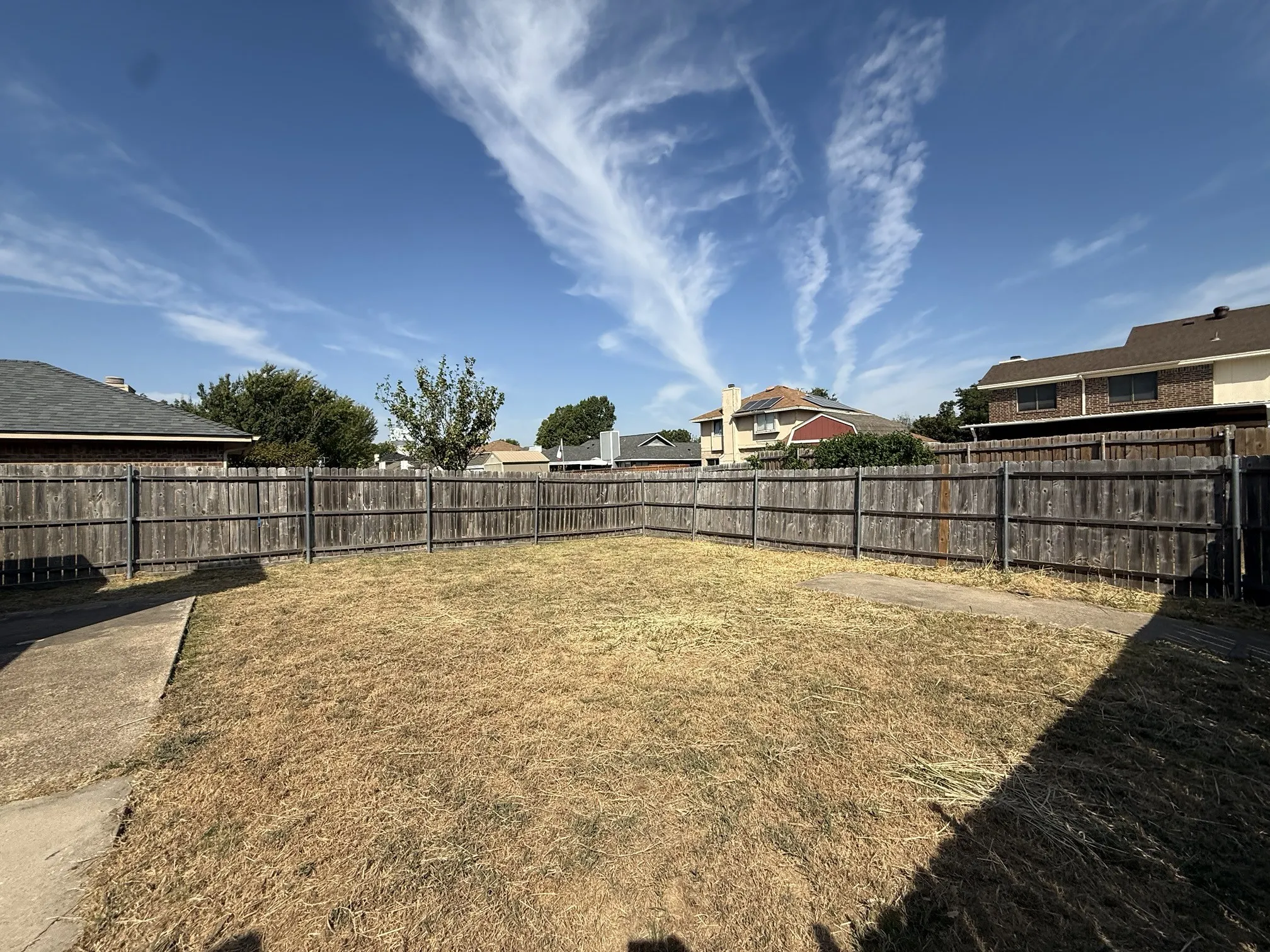 Expansive backyard with wood fencing and a concrete path