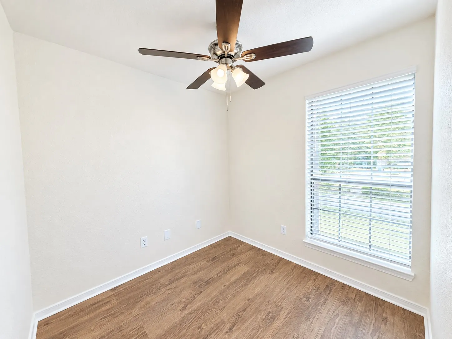 Wood-finish flooring, ceiling fan with light fixture, and a window with blinds