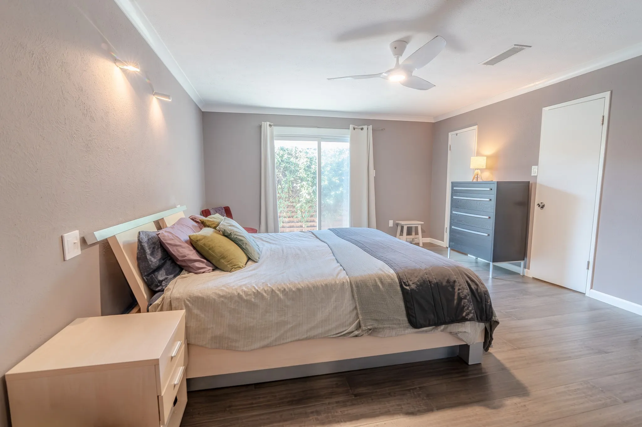 Wood-finish flooring, ceiling fan, sliding glass door, and two panel doors