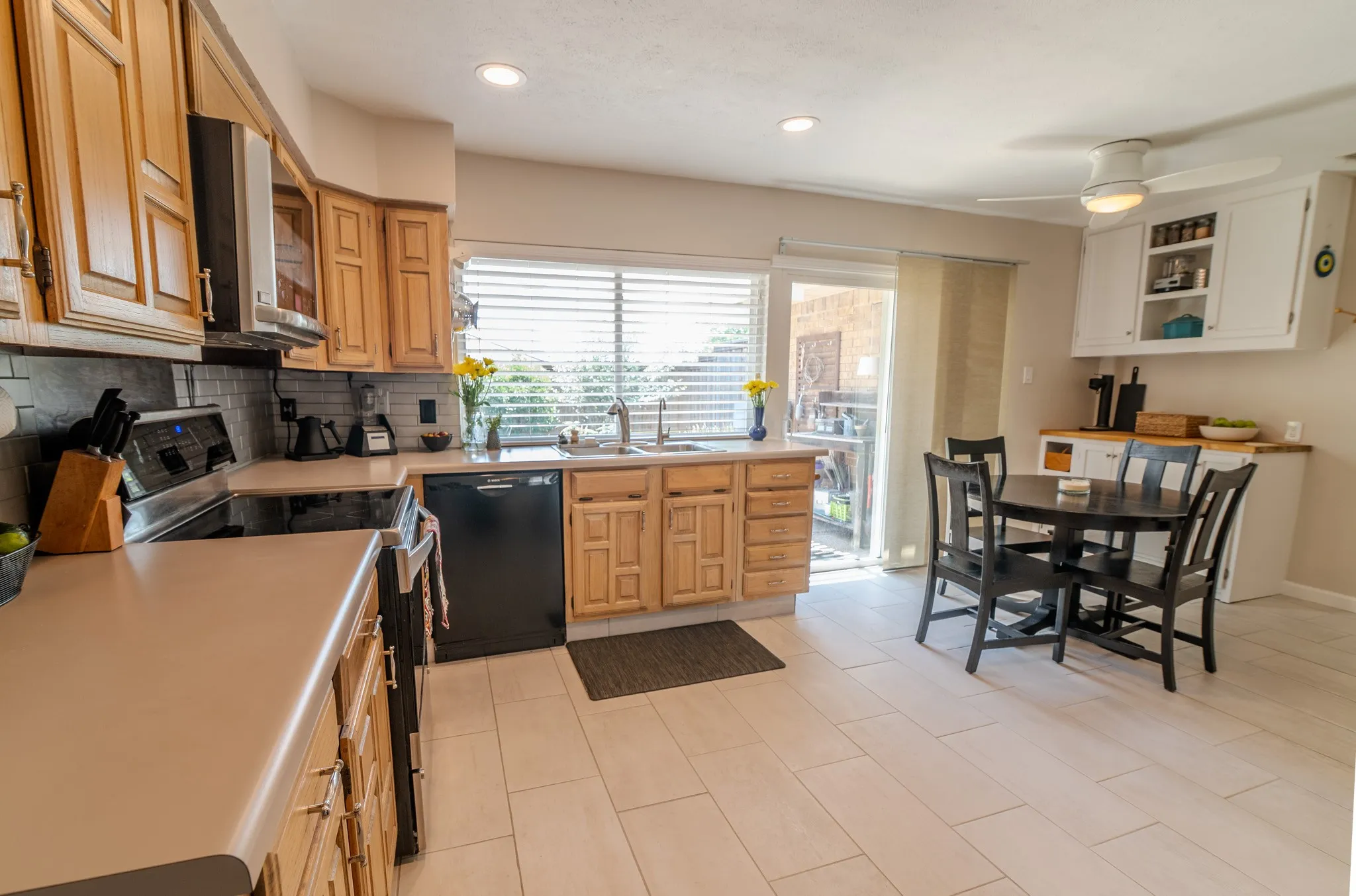 Kitchen featuring light wood cabinetry, light-toned countertops, a black appliance suite, and light plank tile flooring