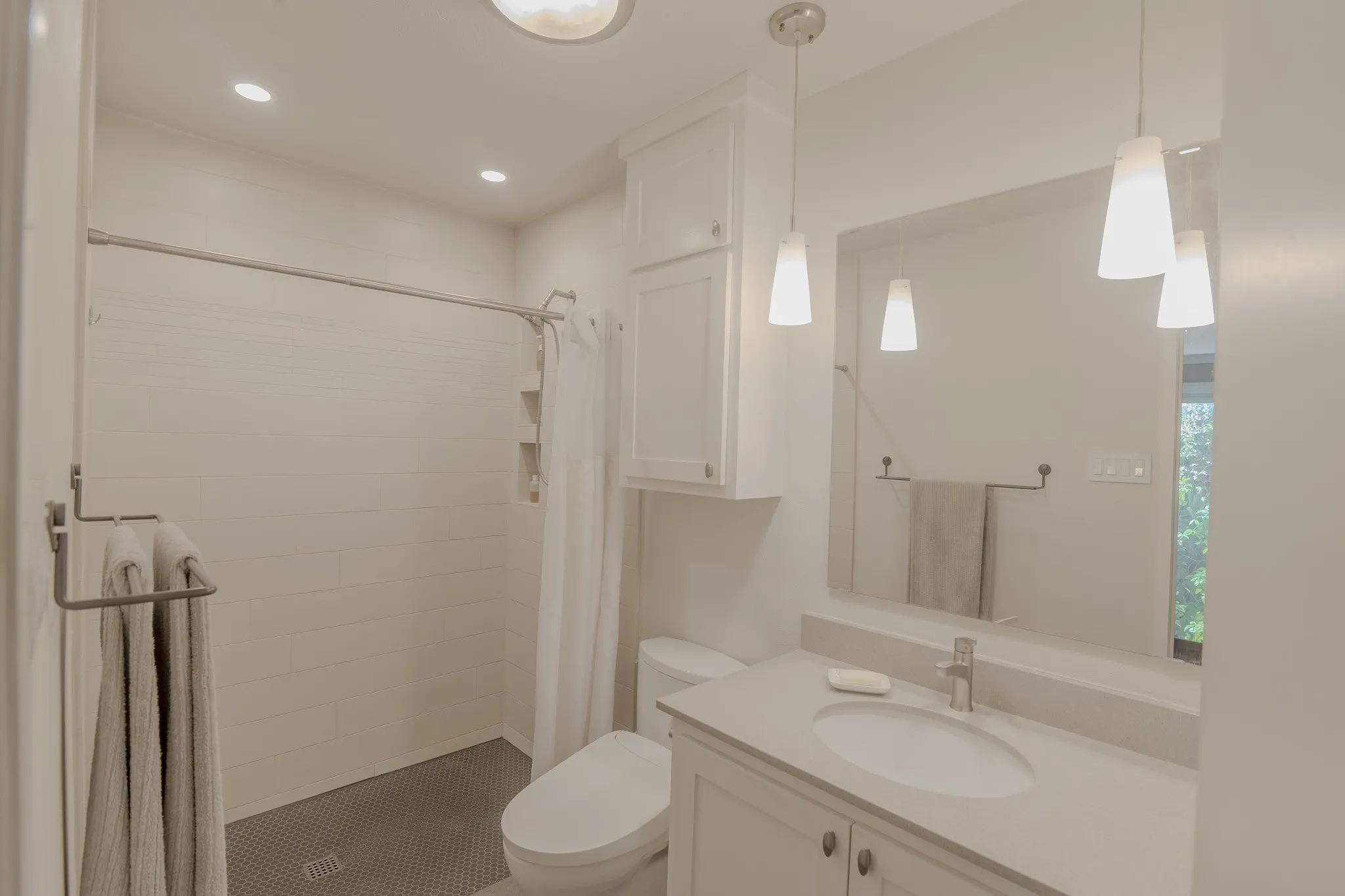 Contemporary bathroom featuring a vanity with an integrated sink, quartz countertop, and pendant lighting