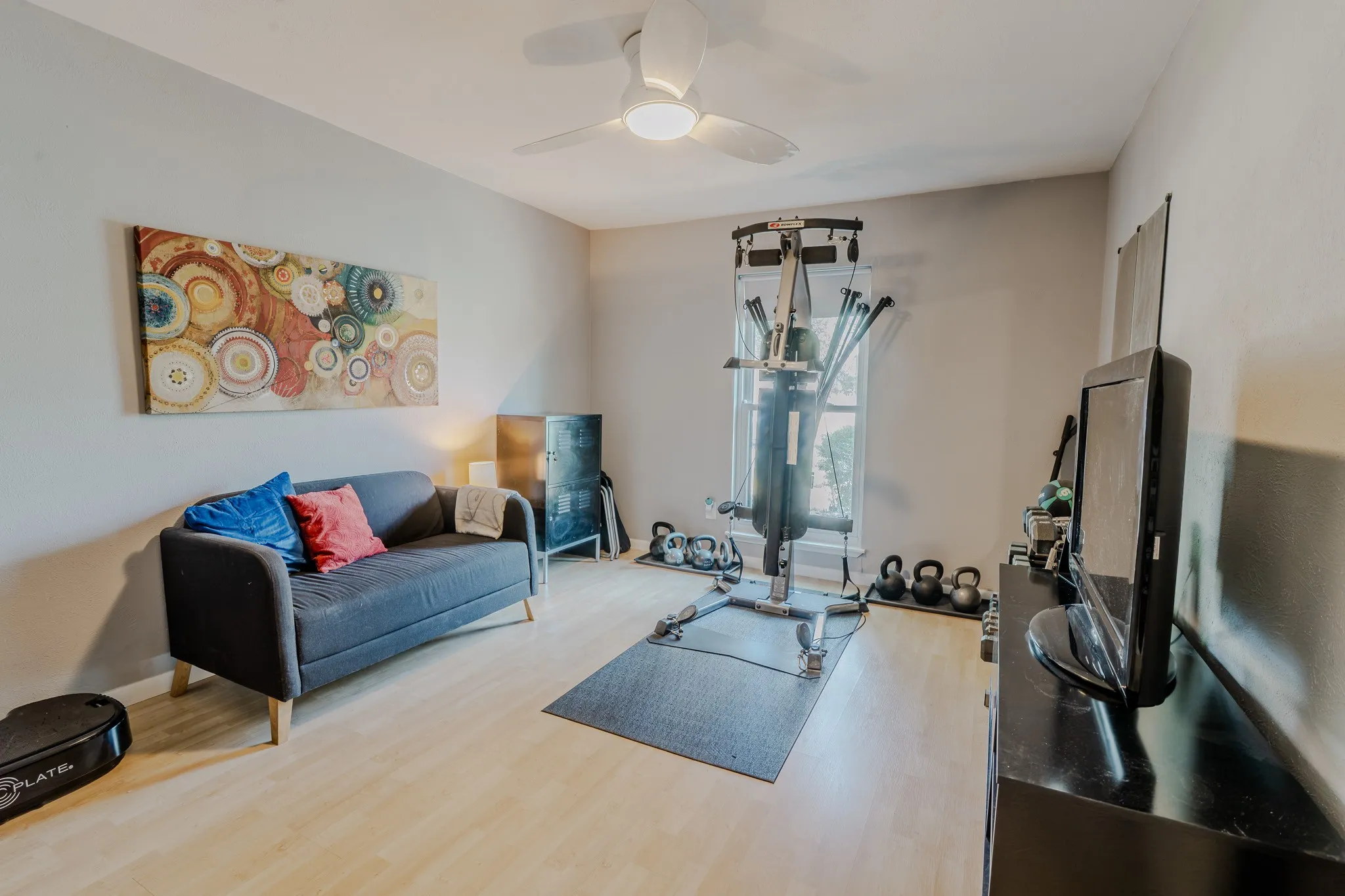 Neutral wall color, ceiling fan, natural light from a window, and light wood-finish flooring