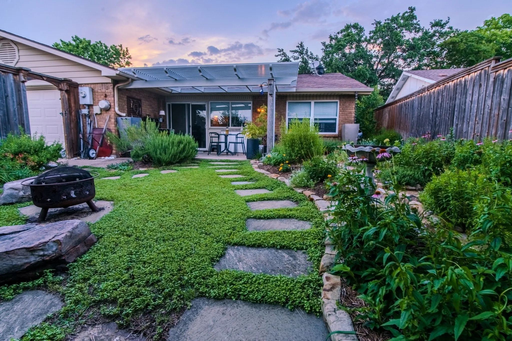 Expansive backyard featuring a stone patio, stepping stone pathway, and mature landscaping