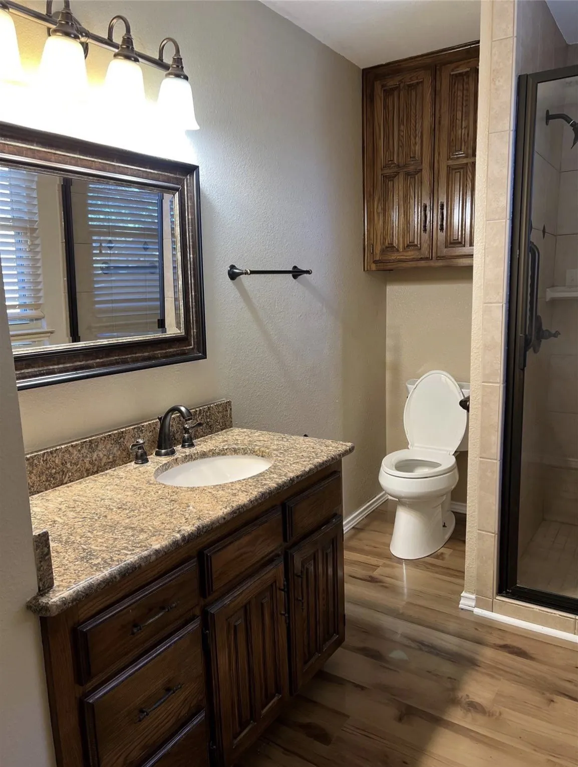 Vanity with a speckled countertop, integrated sink, and dark wood-finish cabinetry