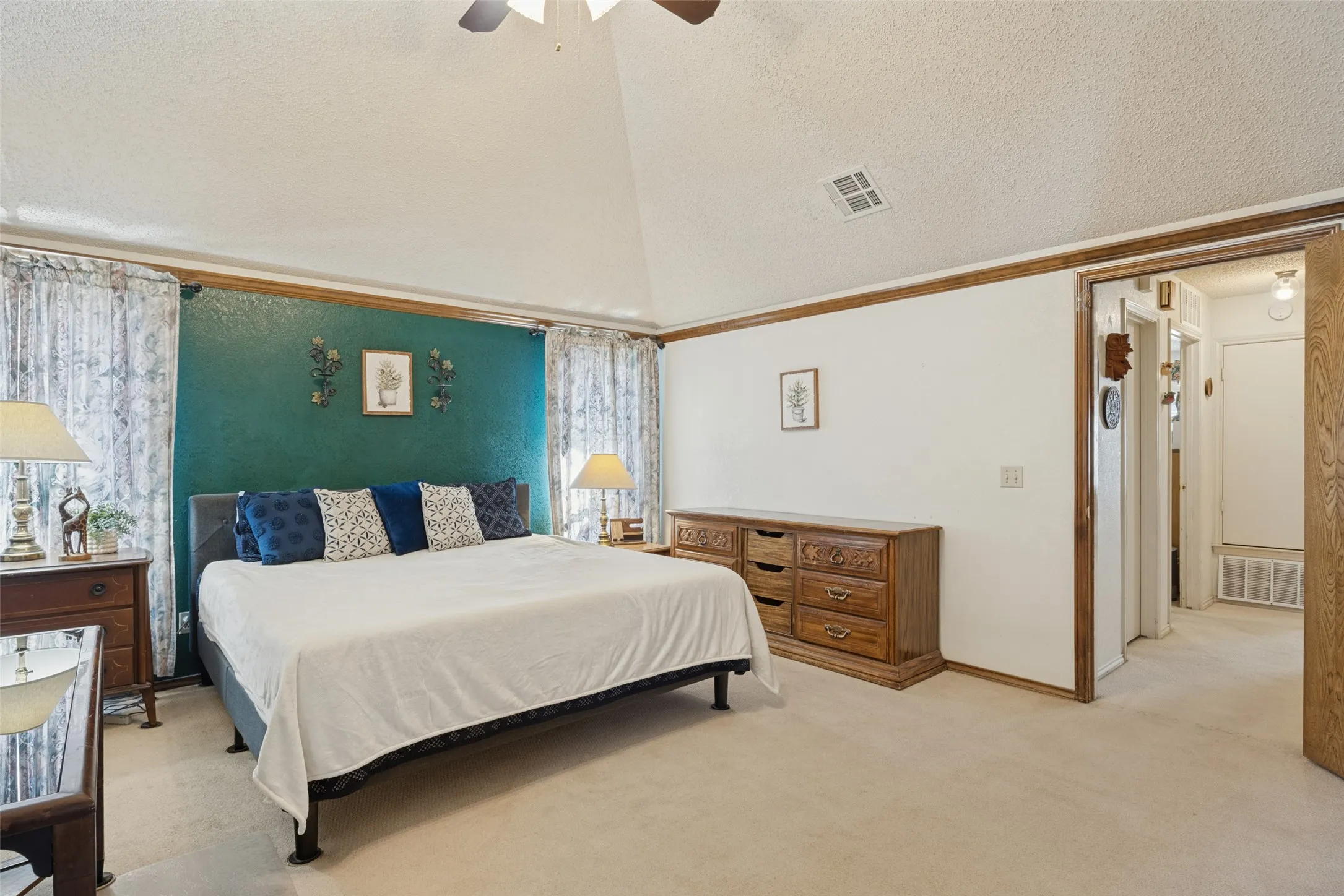 Vaulted ceiling with ceiling fan, wall-to-wall carpeting, and wood trim details