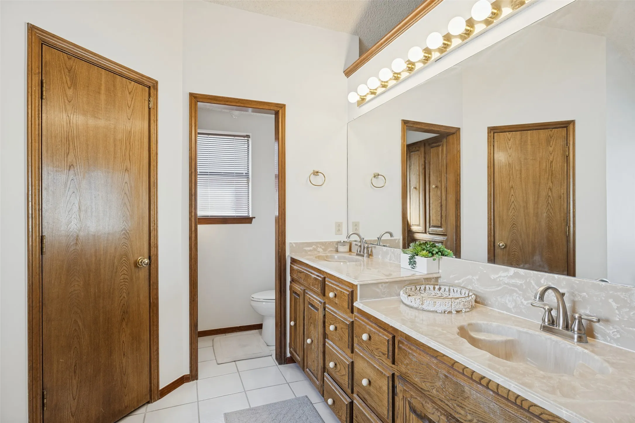 Dual vanity with integrated sinks, wood-finish cabinetry, and a full-width mirror, Dual closets.