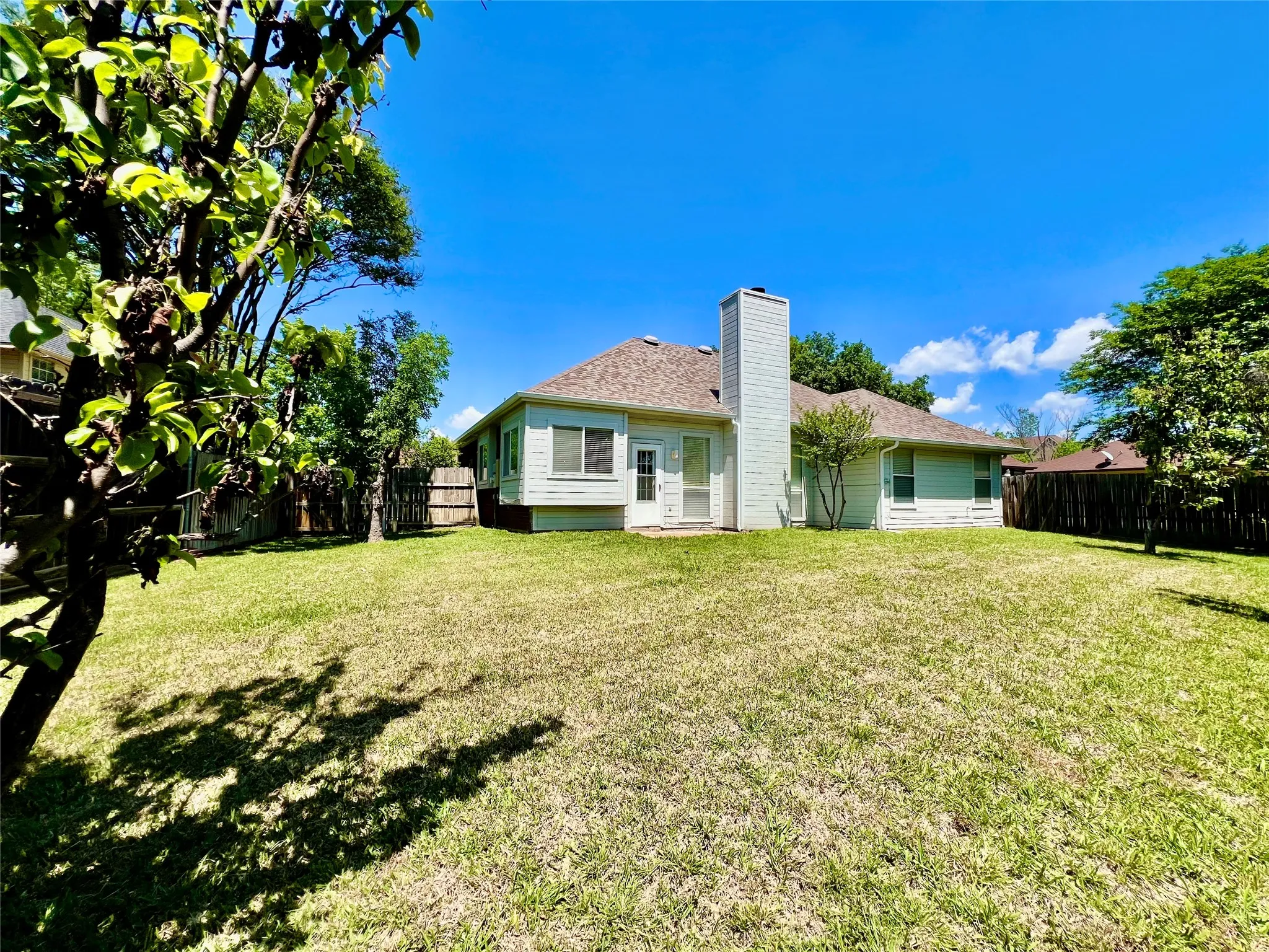 Back of house with a yard, roof with shingles, a chimney, and a fenced backyard