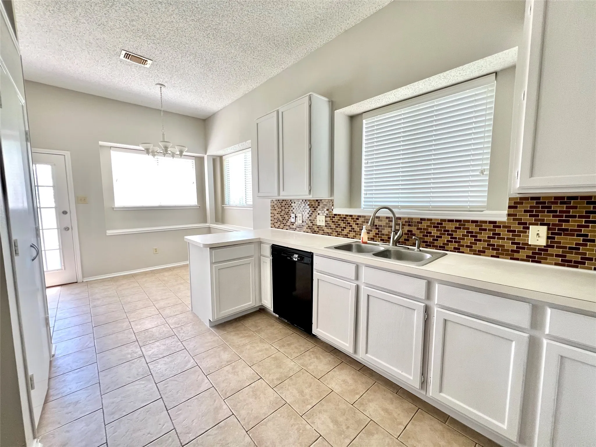 Kitchen featuring dishwasher, a sink, light tile patterned floors, and tasteful backsplash