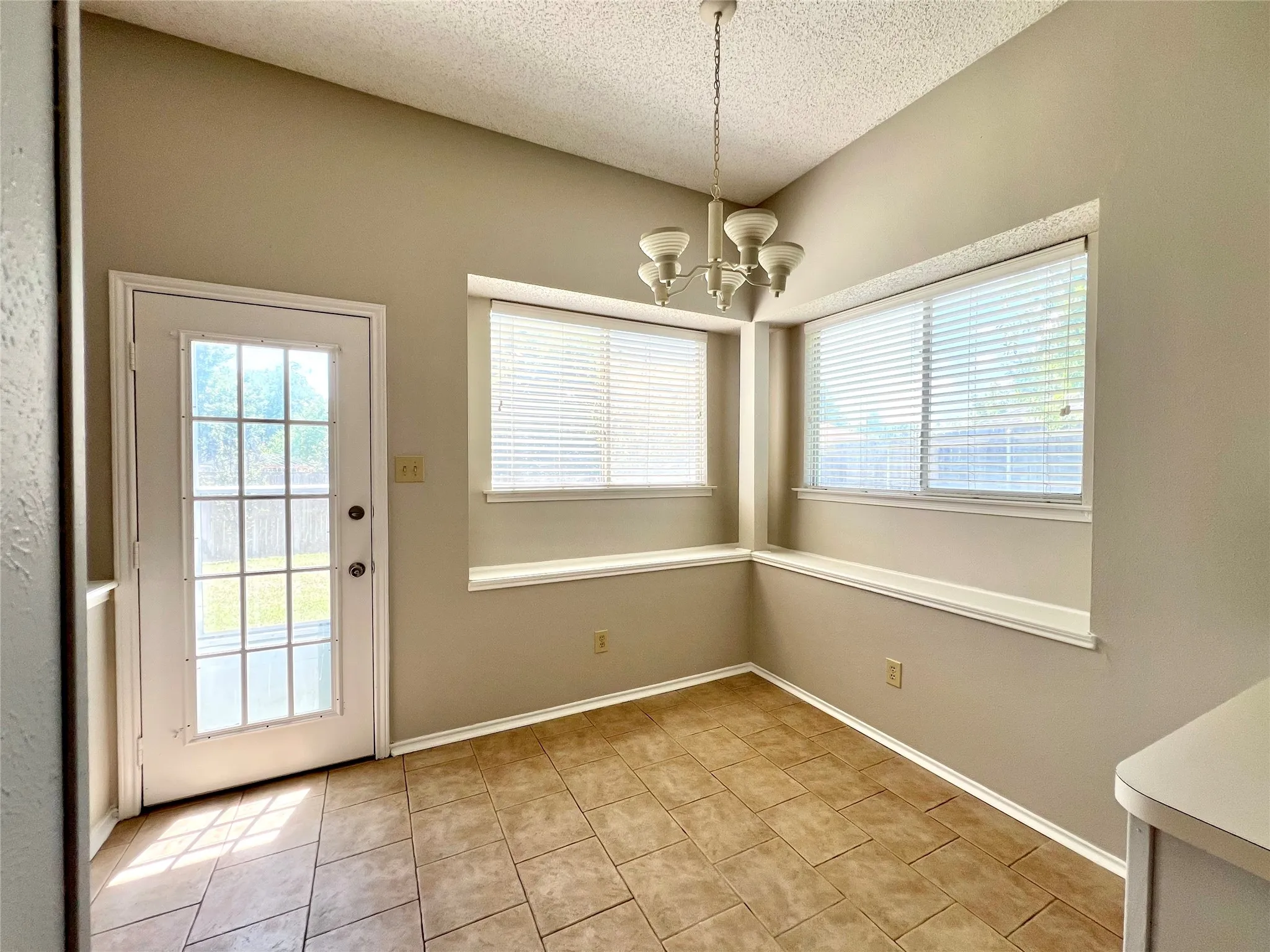 Entryway featuring a chandelier, a textured ceiling, baseboards, and light tile patterned flooring