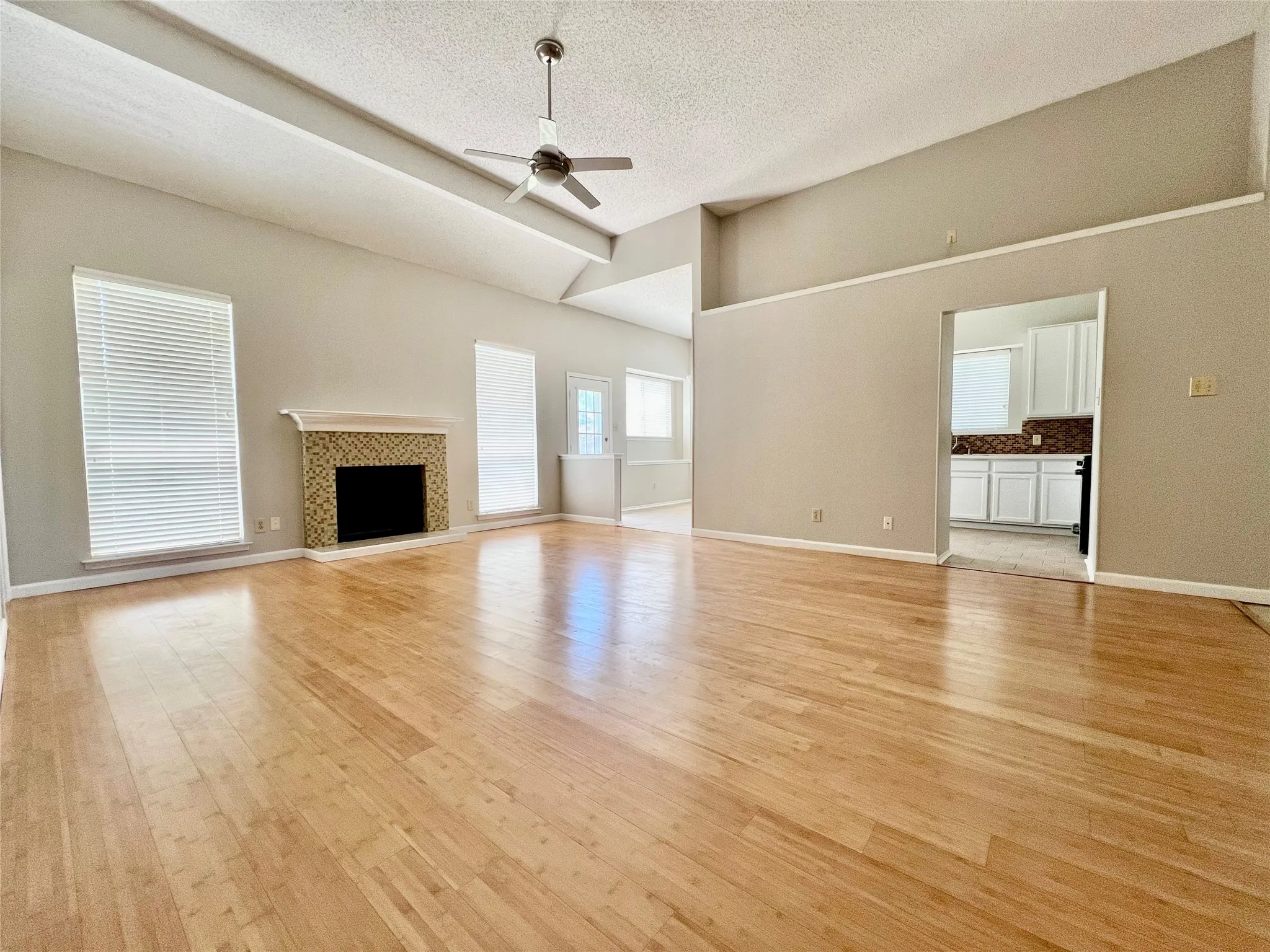 Unfurnished living room with ceiling fan, baseboards, and light wood finished floors