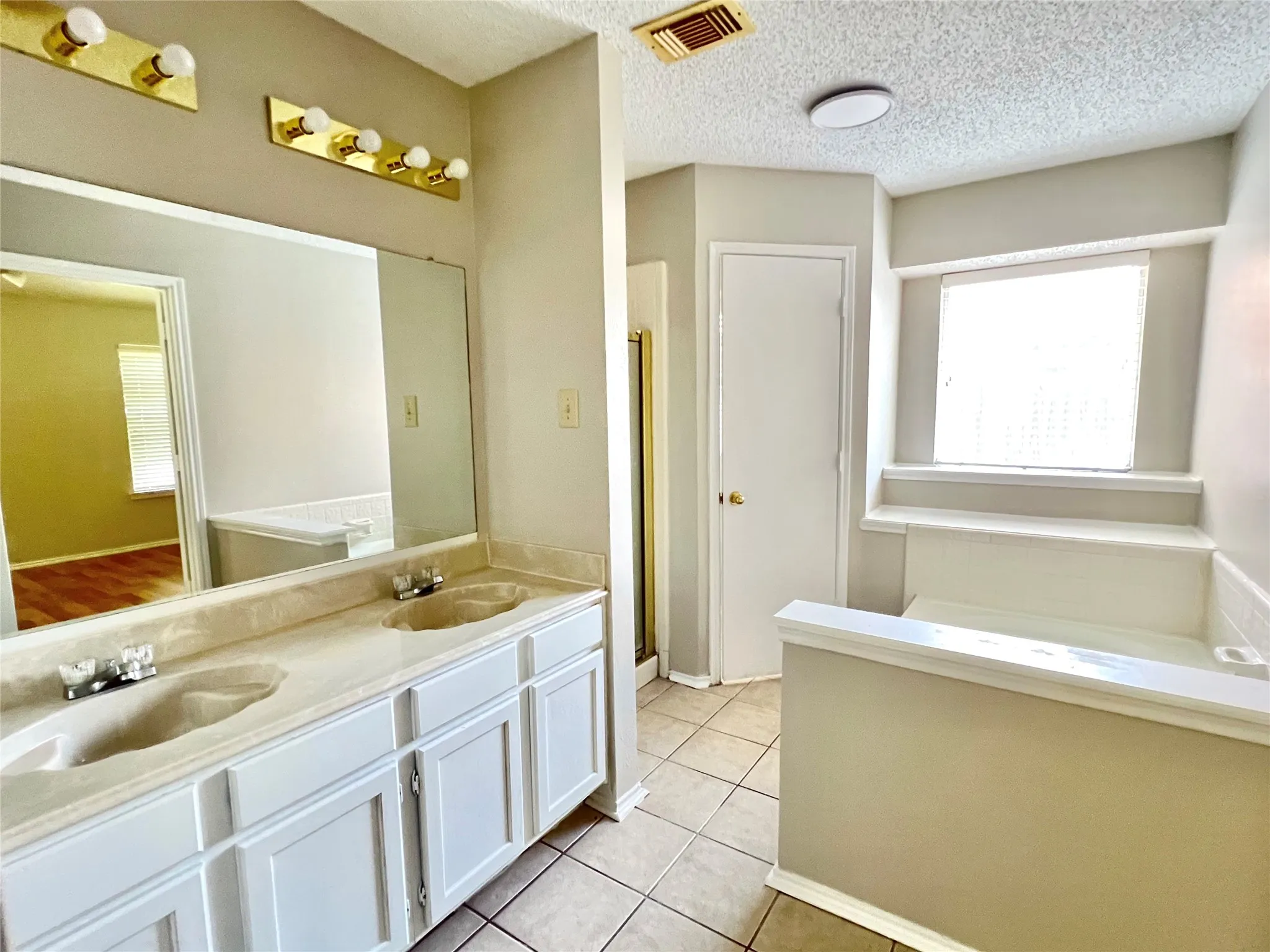 Full bath featuring double vanity, visible vents, tile patterned flooring, and a sink