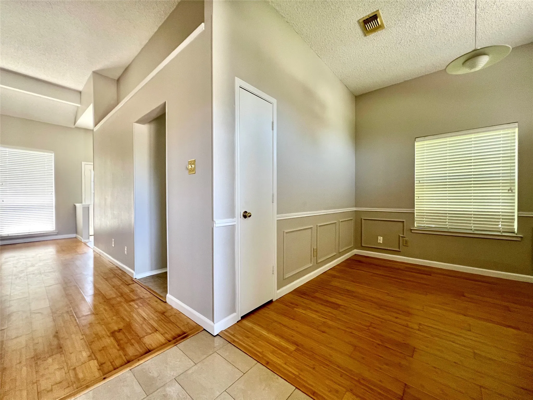 Unfurnished room featuring a textured ceiling, a healthy amount of sunlight, and visible vents