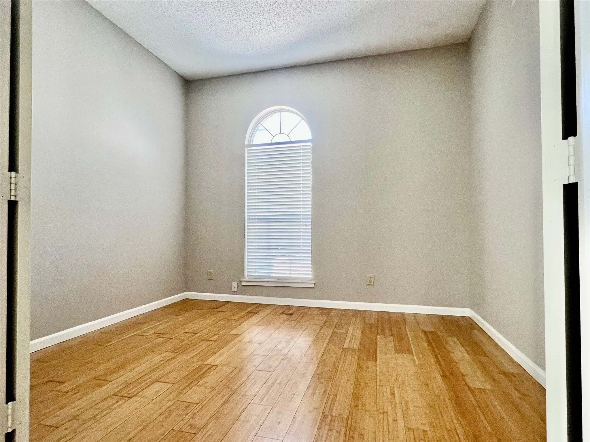 Spare room featuring baseboards, a textured ceiling, and light wood-style floors