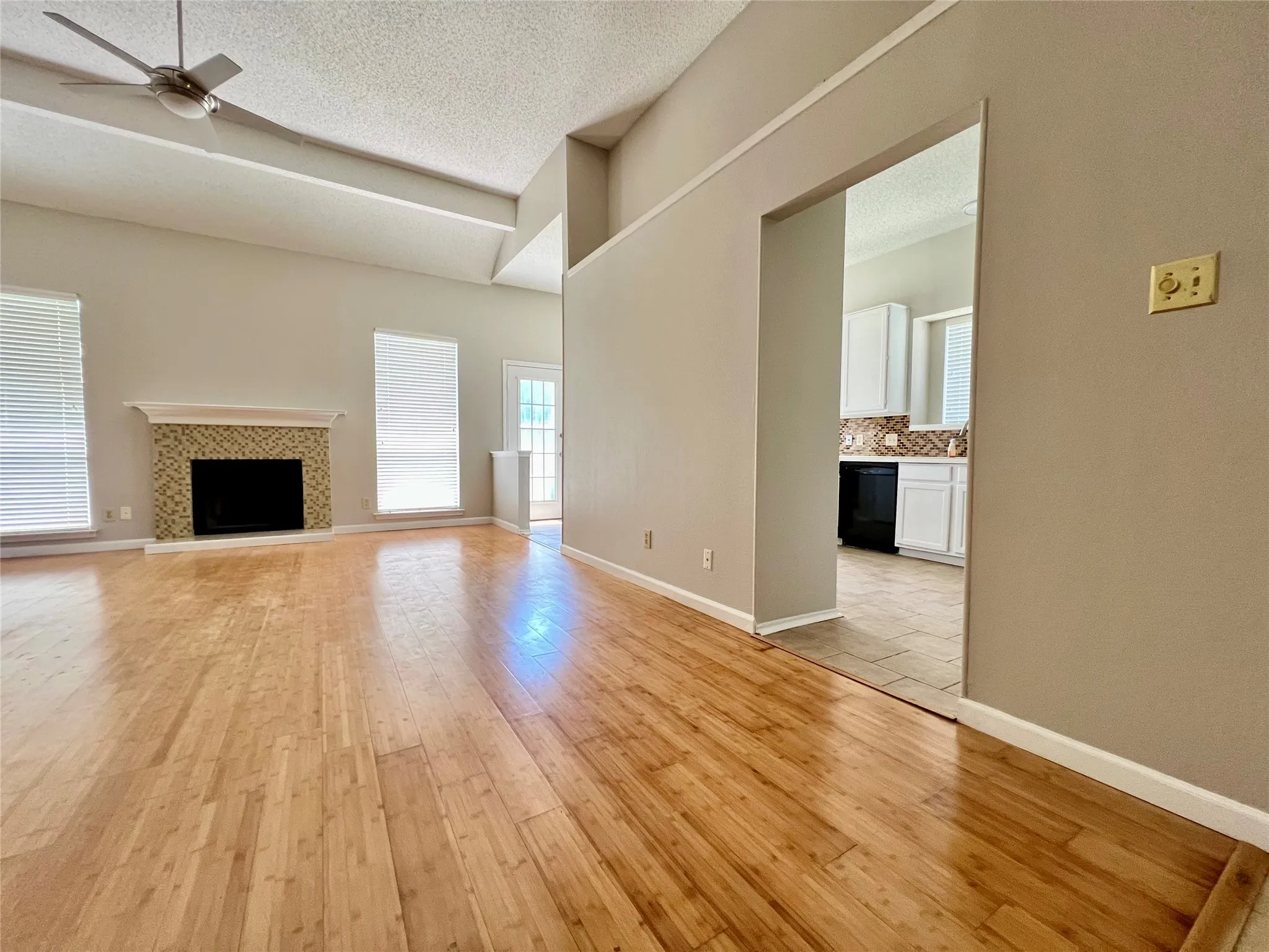 Unfurnished living room with ceiling fan, a textured ceiling, light wood finished floors, and a fireplace