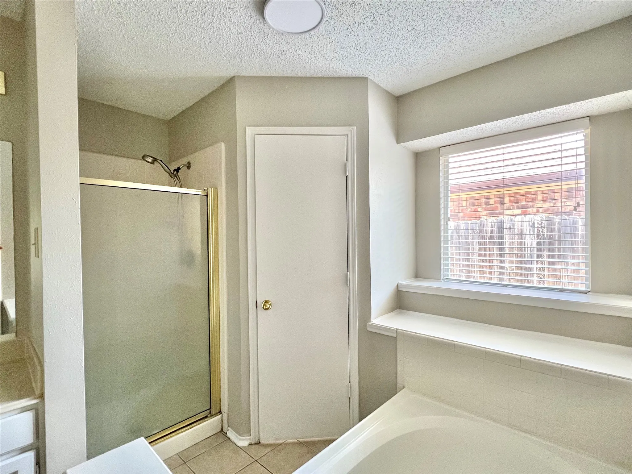 Full bathroom featuring a bath, tile patterned flooring, a textured ceiling, and a stall shower