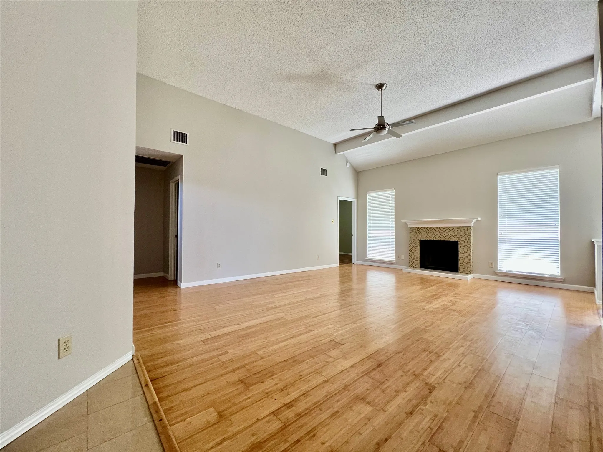 Unfurnished living room featuring ceiling fan, a textured ceiling, visible vents, and light wood-type flooring