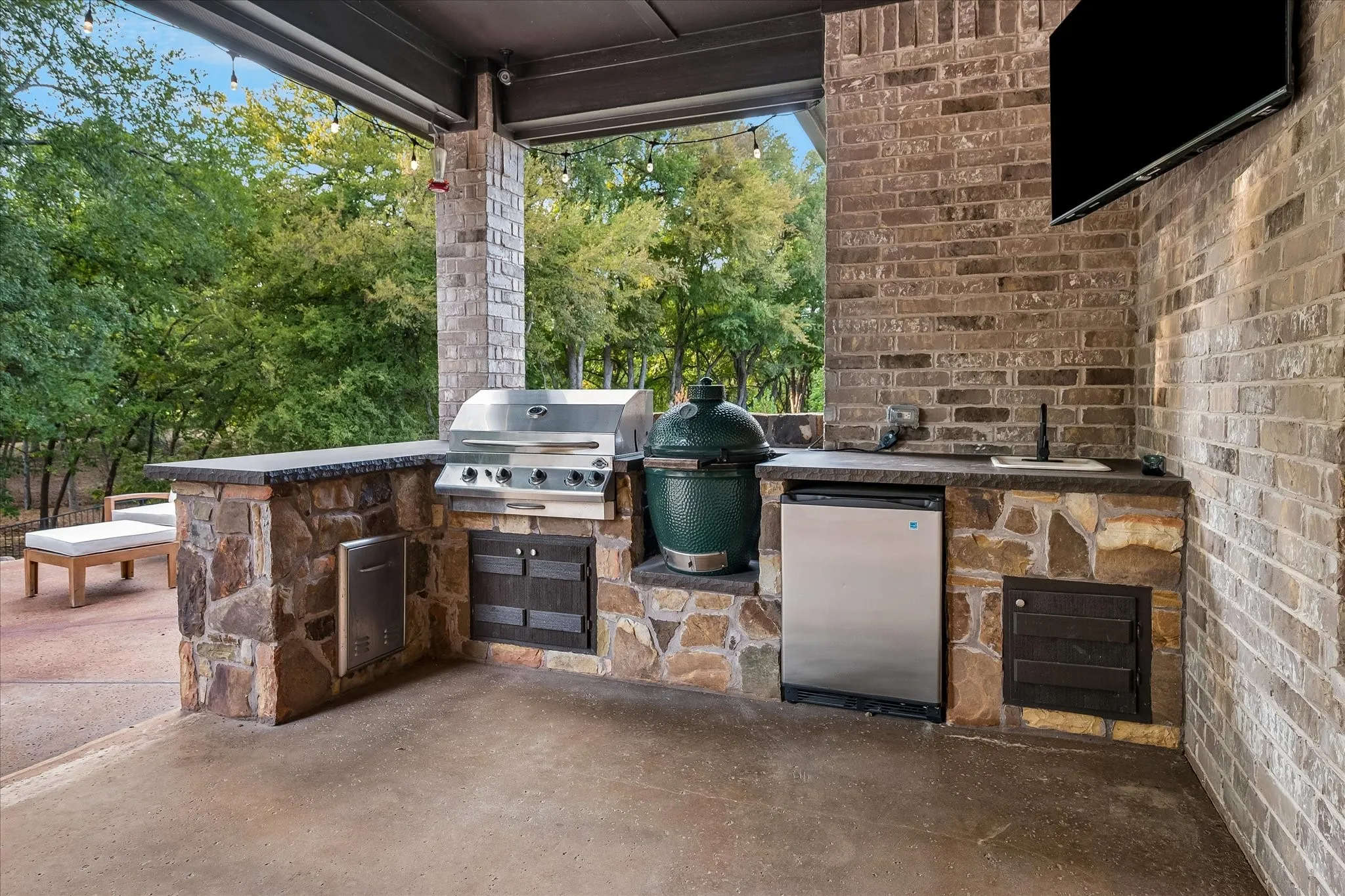 Covered outdoor kitchen overlooking pool and lush green space — perfect for morning coffee or sunset by the water.