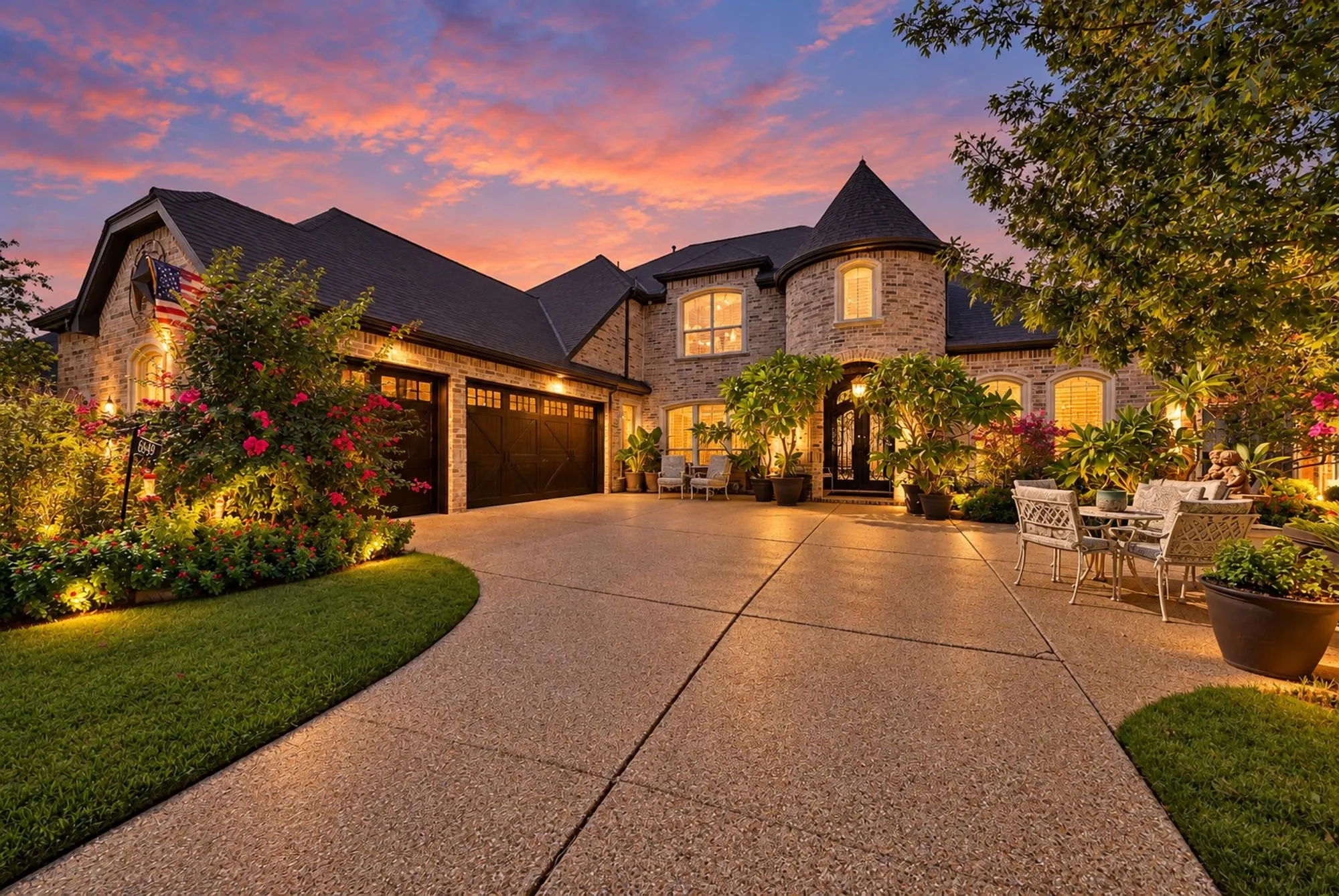 Luxury takes center stage at twilight, highlighting the home’s impressive architecture, generous parking, and statement-making glass garage doors.