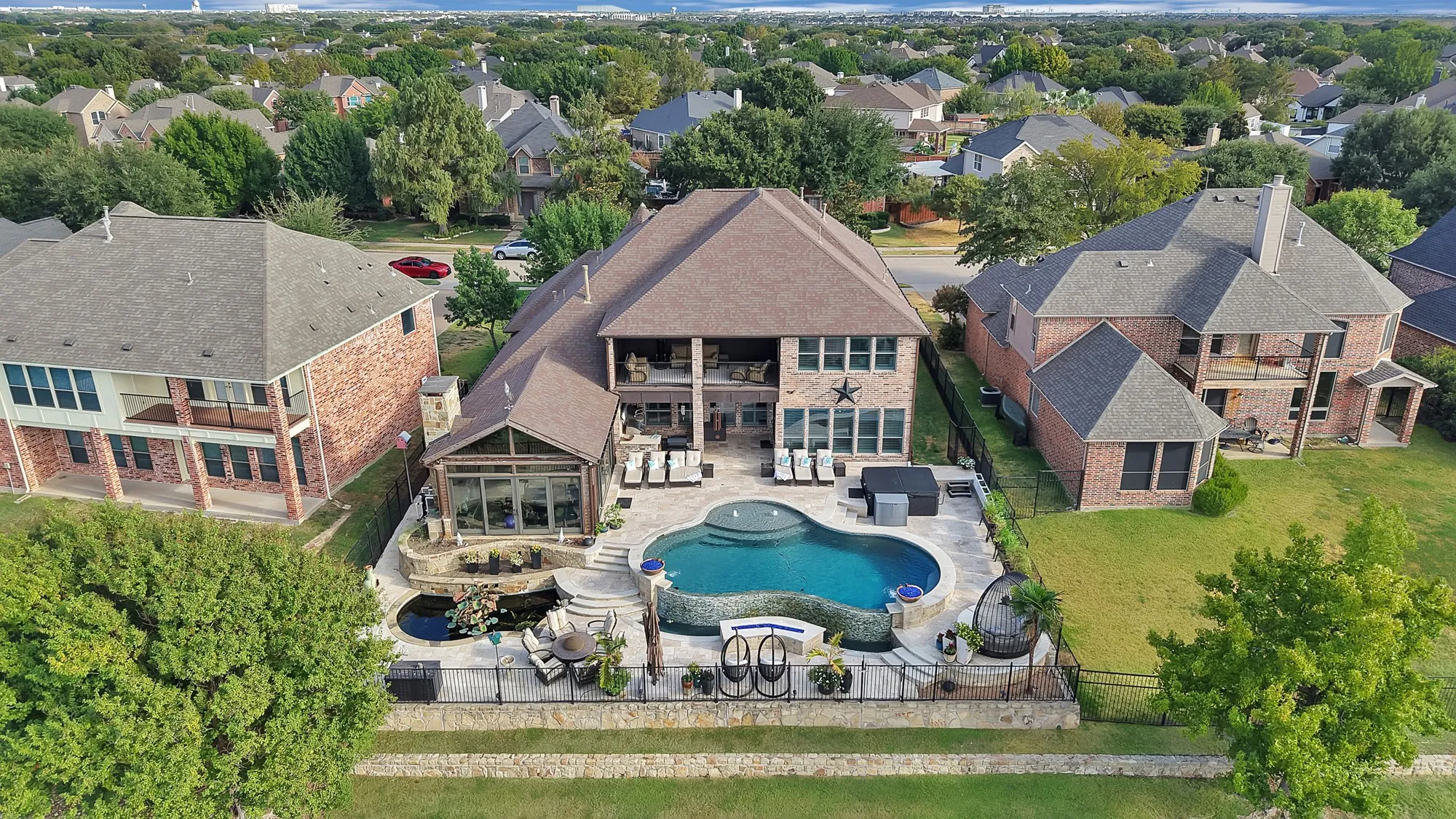 **An extraordinary aerial view showcases the property in its entirety, highlighting the expansive home, resort-style outdoor oasis, and beautiful surrounding landscape in one breathtaking perspective.**
