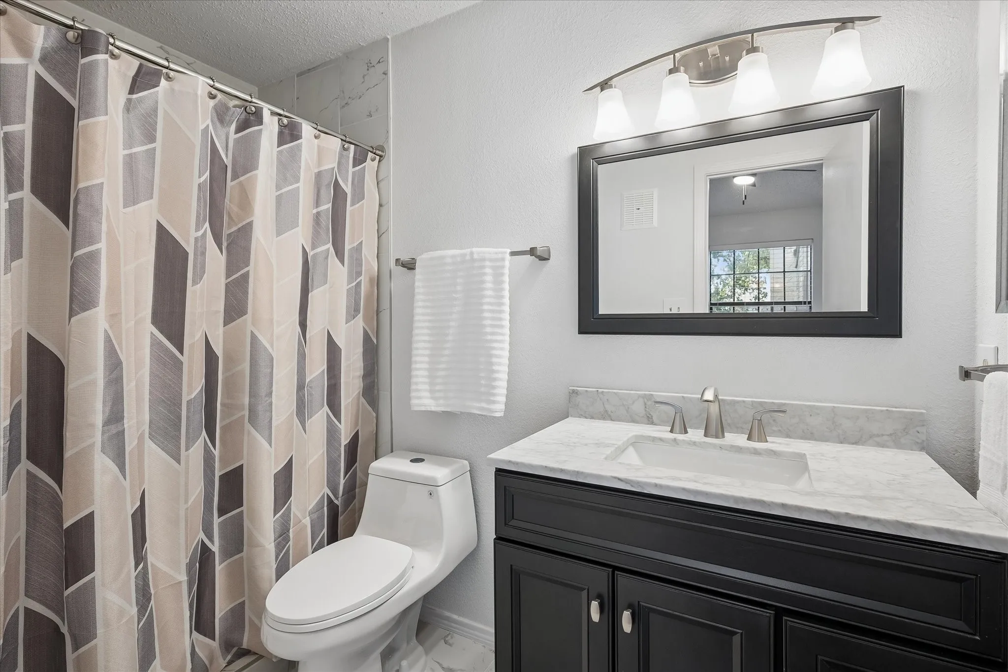 Primary bathroom has medicine cabinet and has a crisp look with all its great updates.
