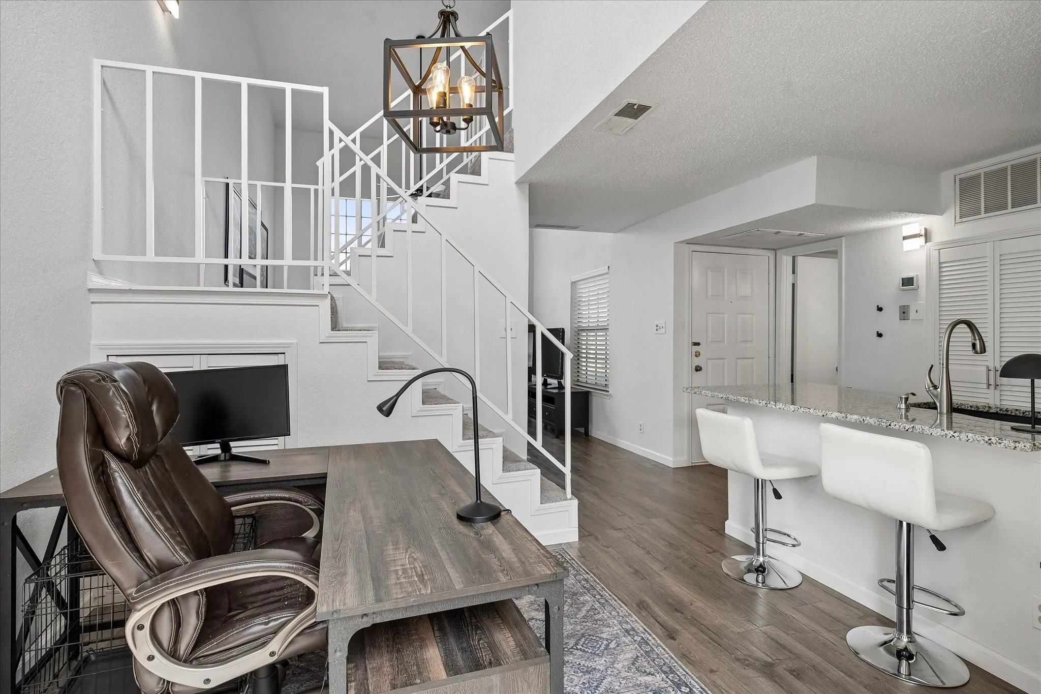 View of the front door, kitchen, staircase and living area.