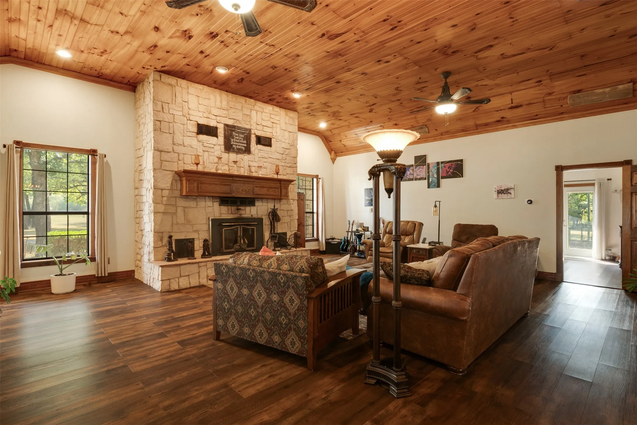 Vaulted wood-paneled ceiling, stone fireplace with a wood mantle, wood-finish flooring, recessed lighting, and a ceiling fan