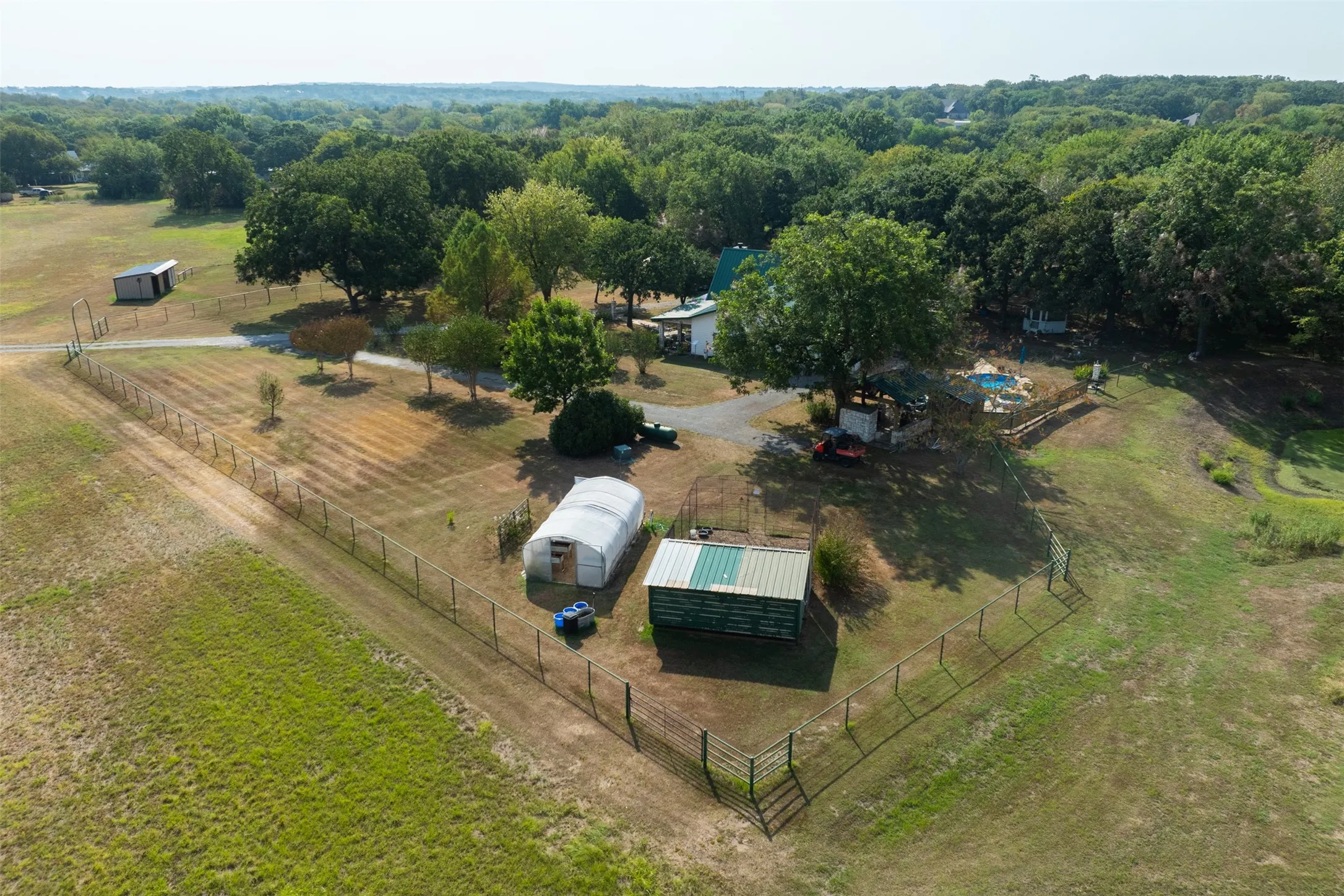 Expansive acreage featuring fencing, mature trees, a detached storage building, and an inground pool