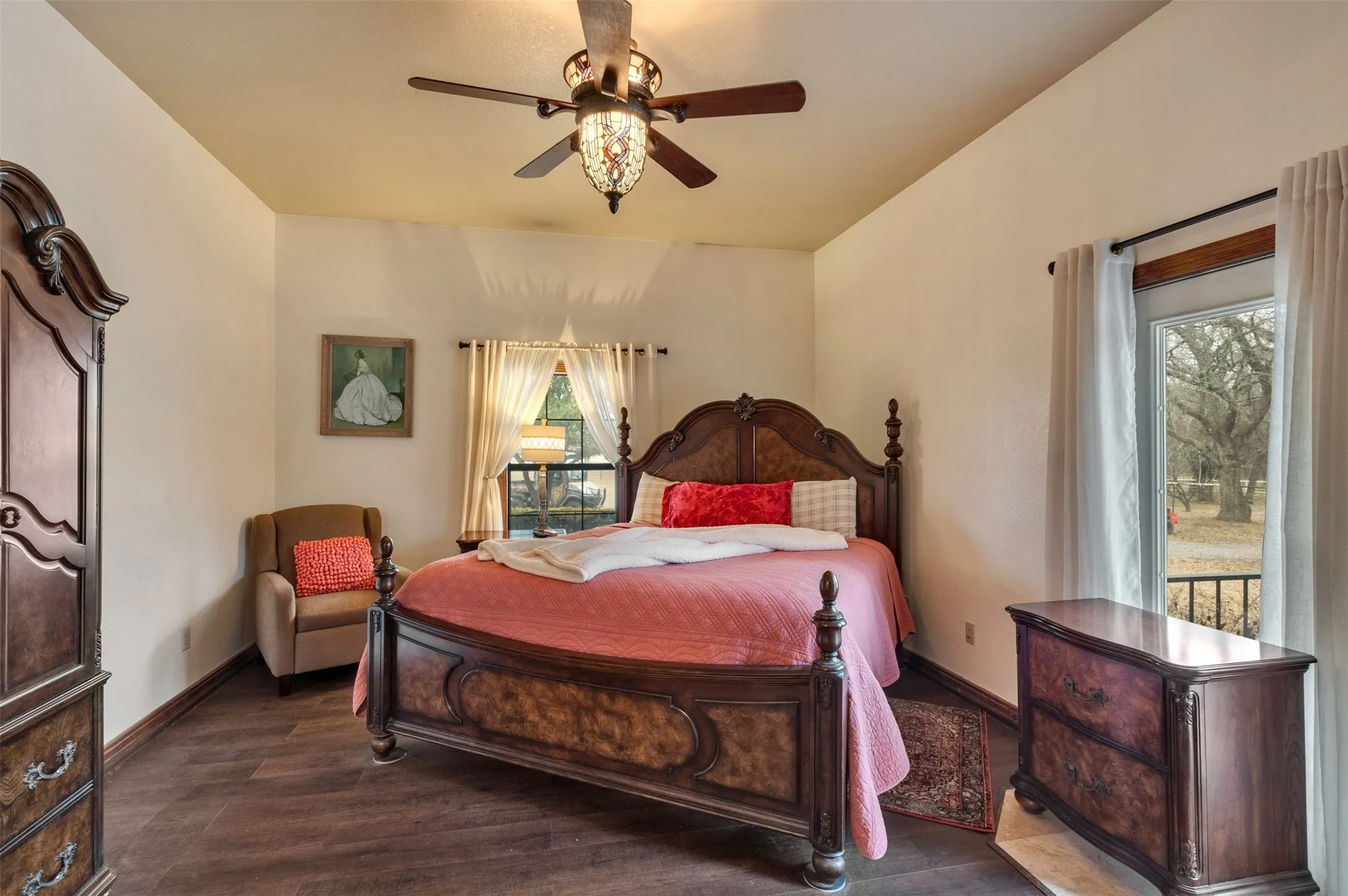 Wood-finish flooring, a ceiling fan with integrated lighting, and a large window with drapes