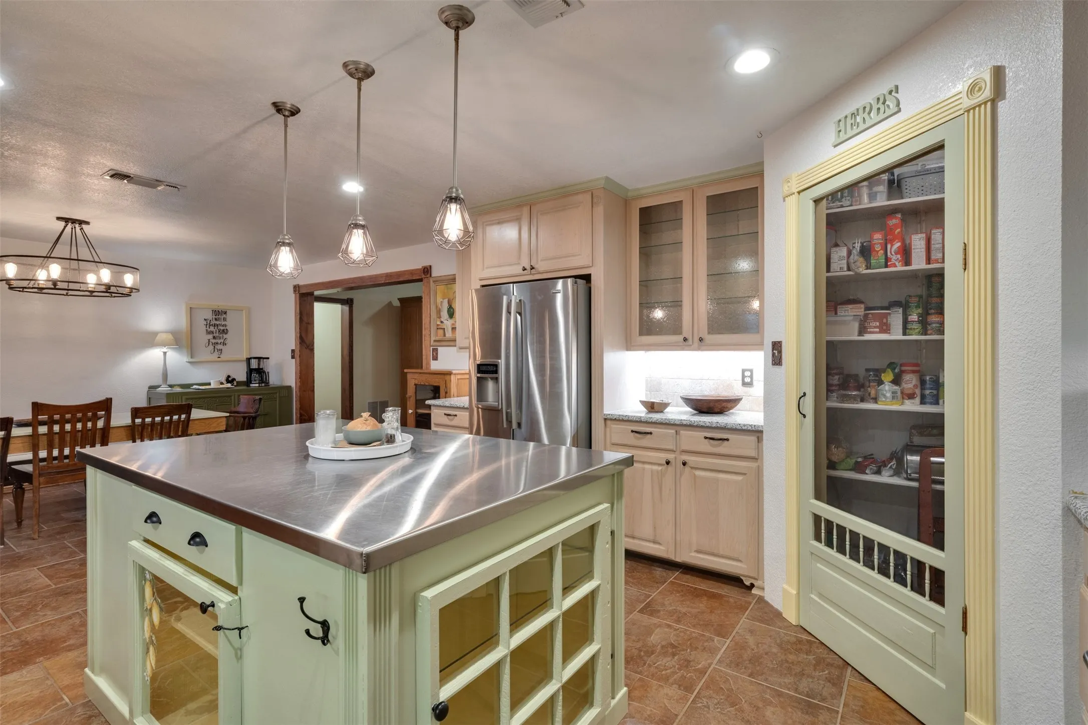 Kitchen featuring a stainless steel island, pendant lighting, built-in shelving, glass-front cabinetry, and granite countertops