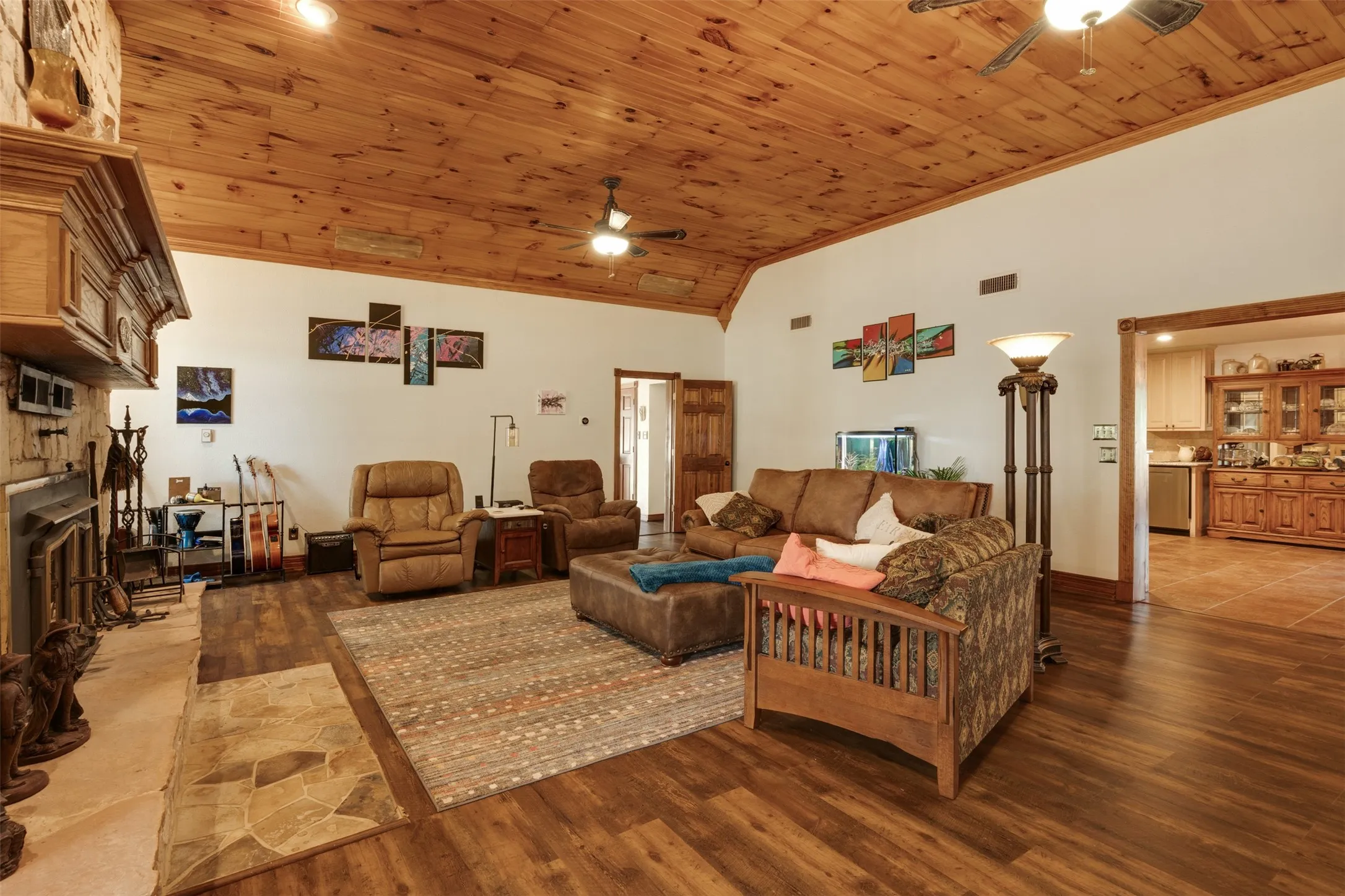 Vaulted wood-paneled ceiling, wood-finish flooring, stone-clad fireplace with mantel, and recessed lighting