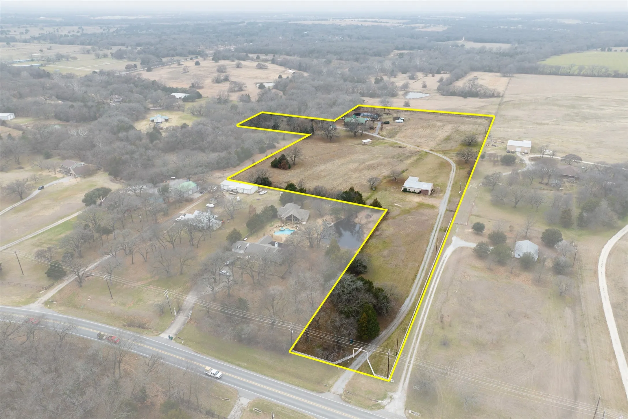 Expansive rural property featuring two residential structures, a private drive, and mature trees