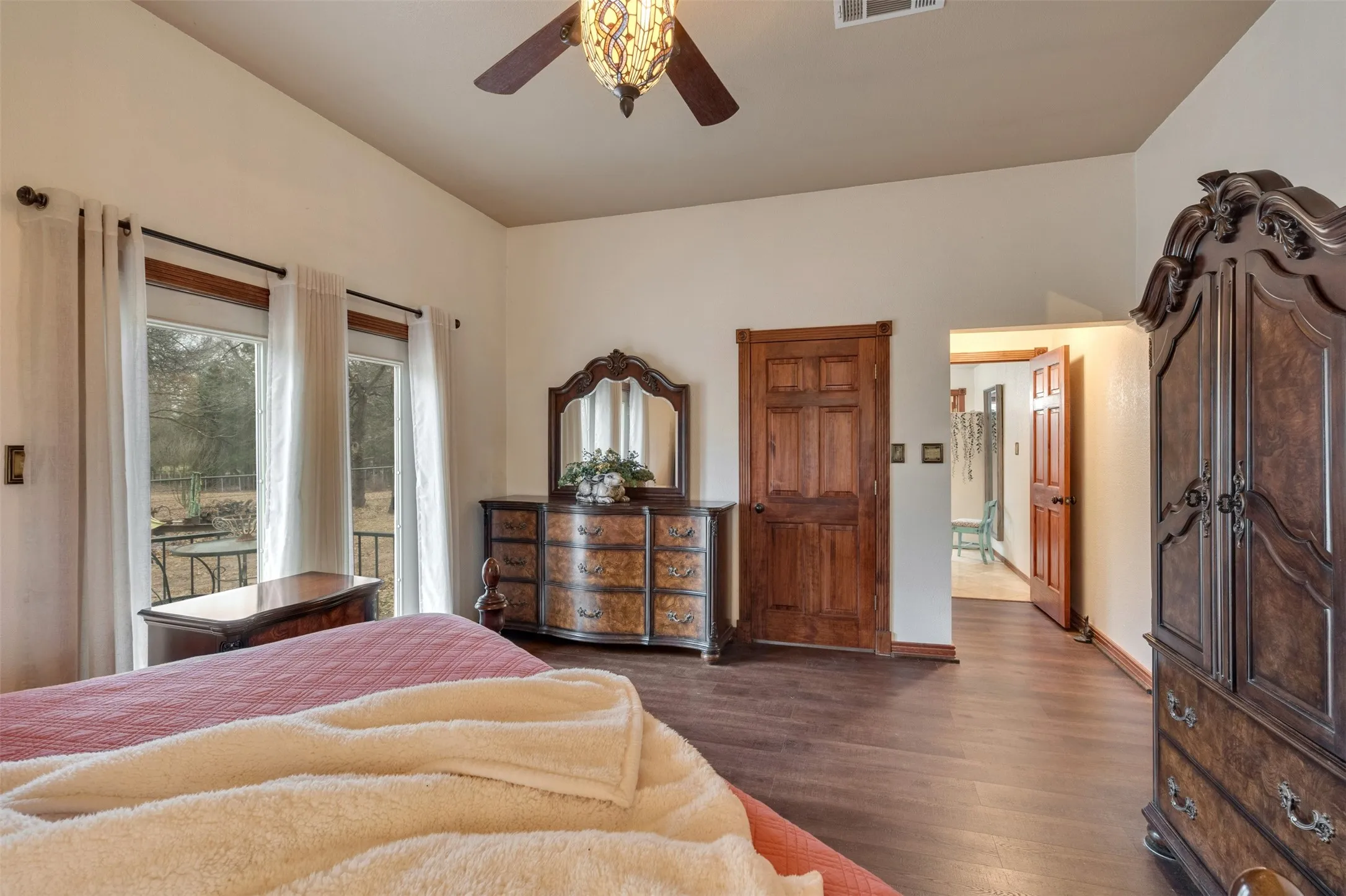 Vaulted ceiling, wood-finish flooring, ceiling fan with light fixture, double French doors, solid wood panel door