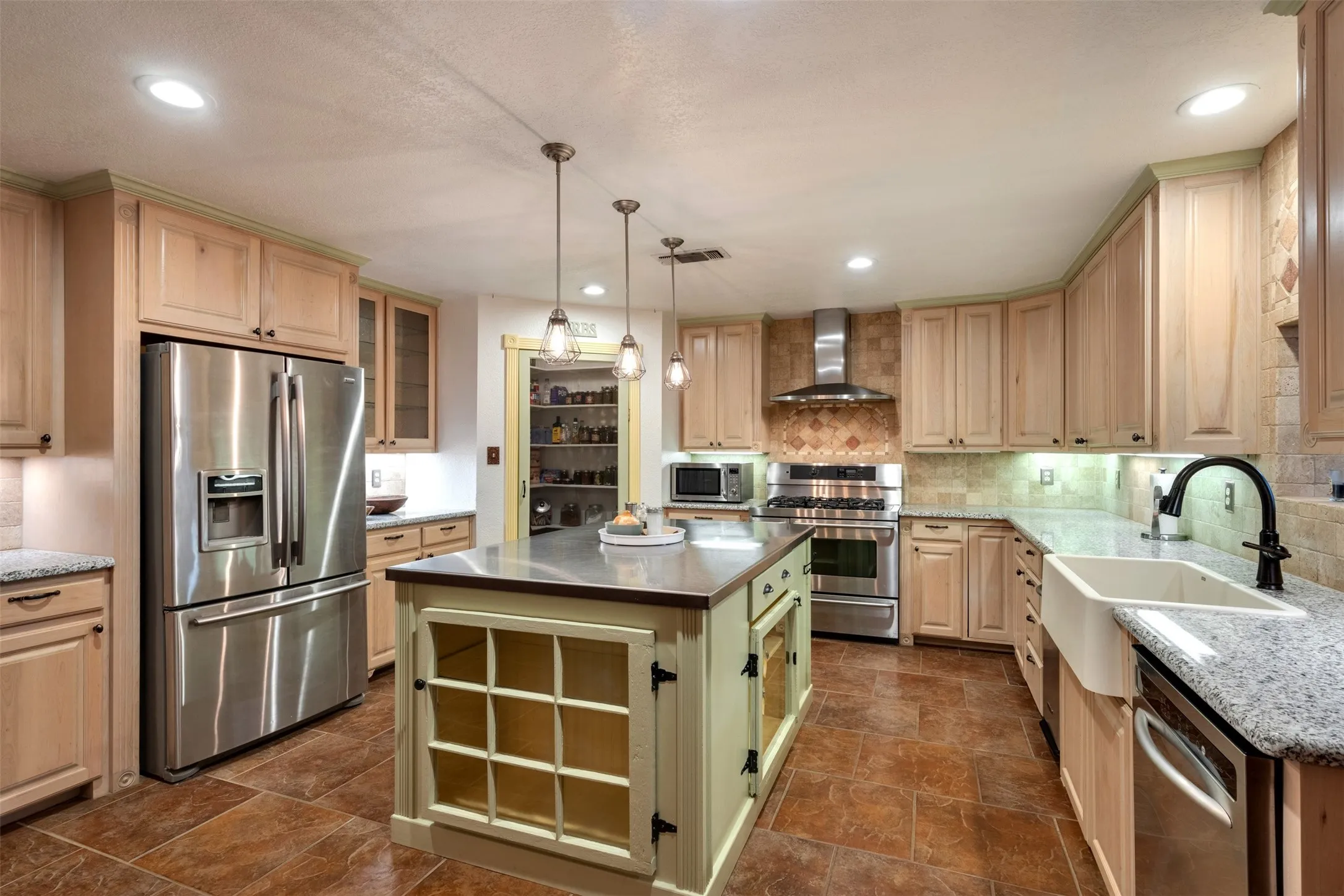 Stainless steel appliances, granite countertops, tile flooring, farmhouse sink, and a center island with pendant lighting