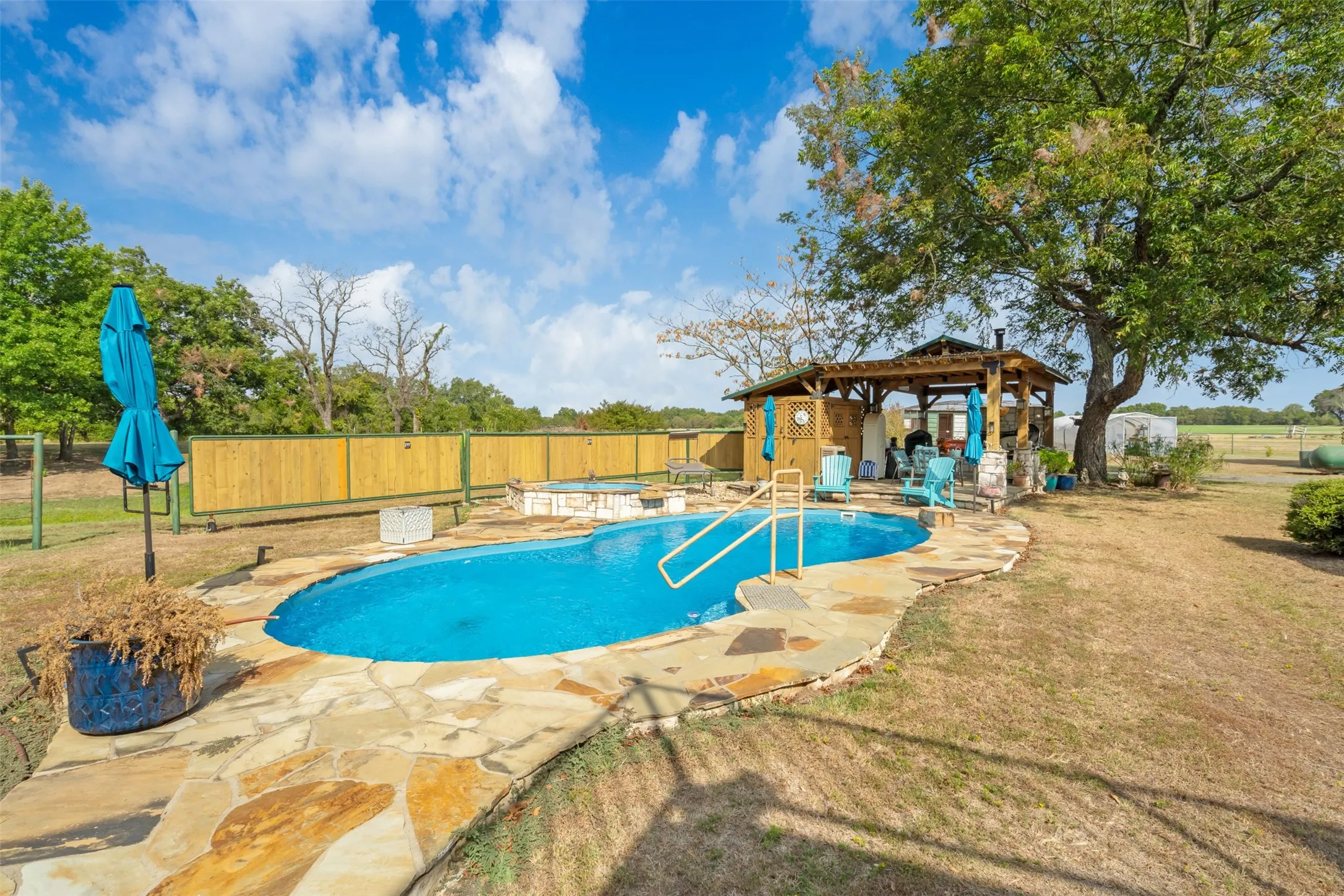 Swimming pool with flagstone surround, adjacent spa, and a wooden gazebo