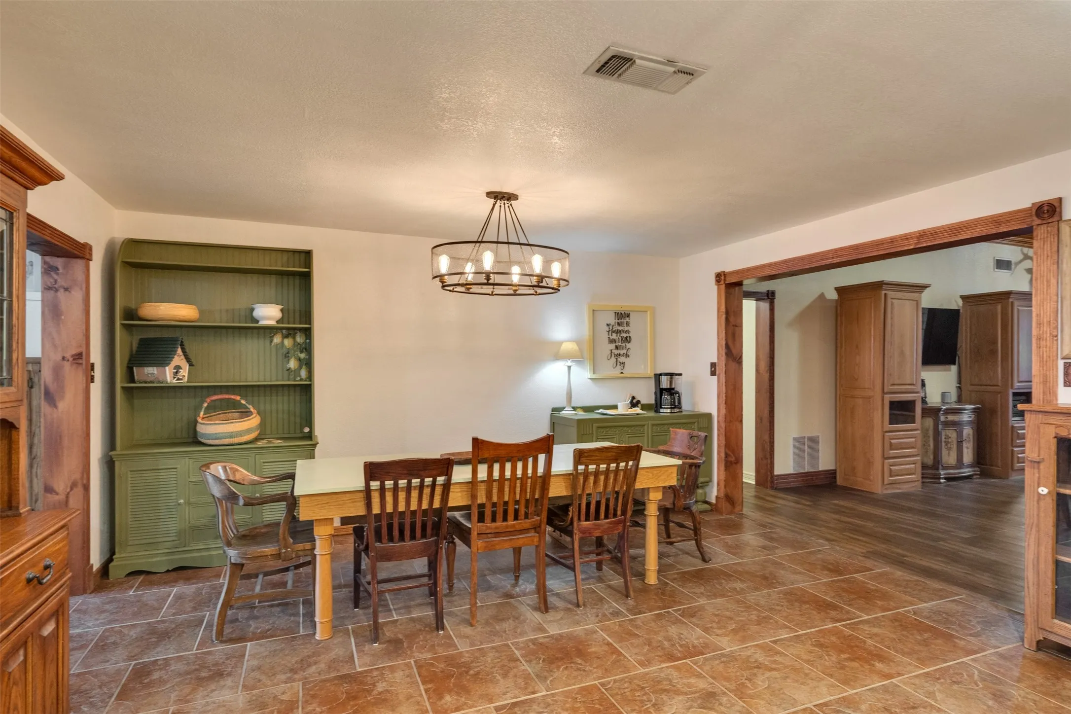 Tile flooring extending to wood-finish flooring, with a prominent wood beam doorway