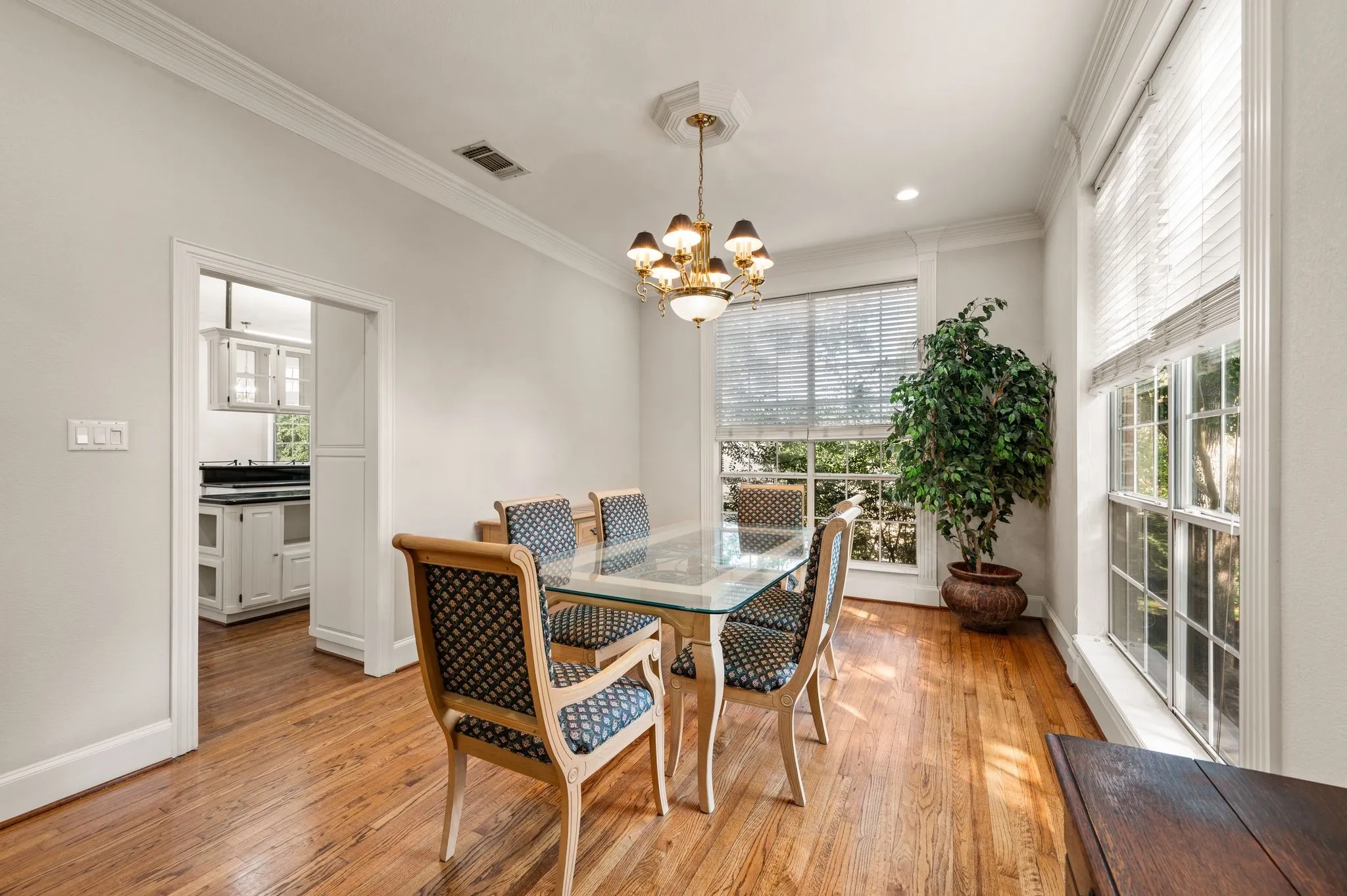 Hardwood flooring, crown molding, large window with blinds, recessed lighting, and a decorative chandelier