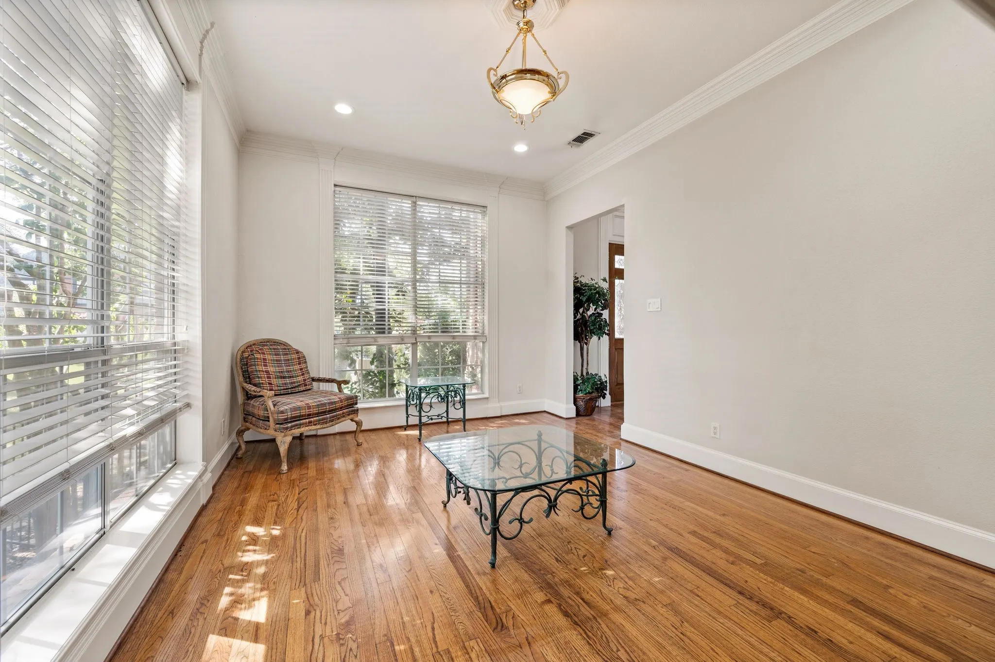 Hardwood flooring, recessed lighting, crown molding, multiple windows, and a classic chandelier