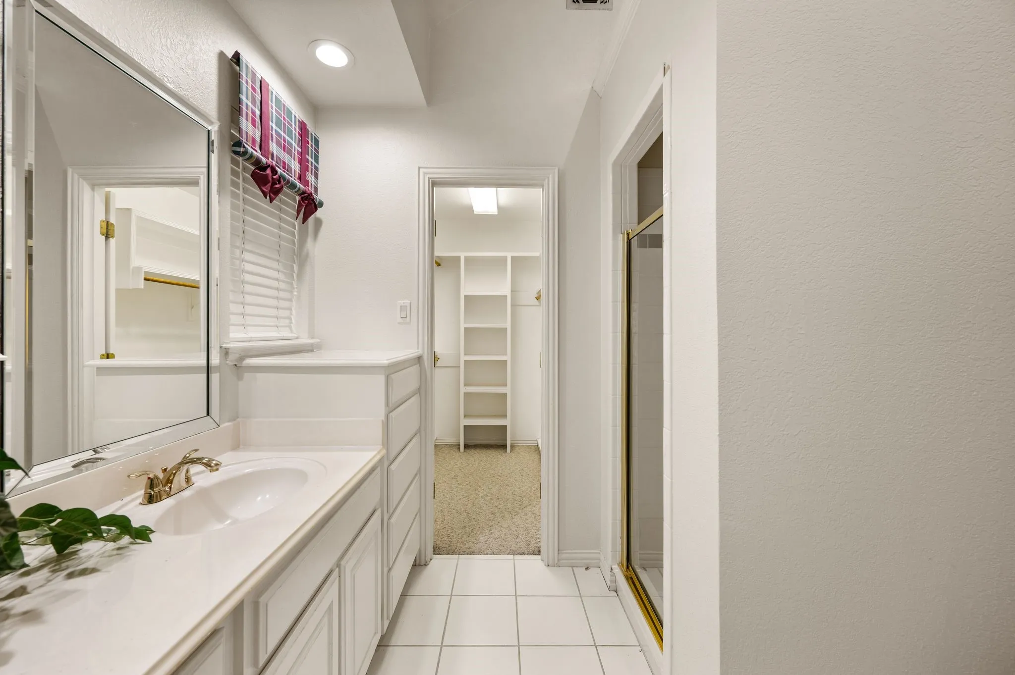 Vanity with an integrated sink and brass-finish faucet, framed mirror, and built-in drawers