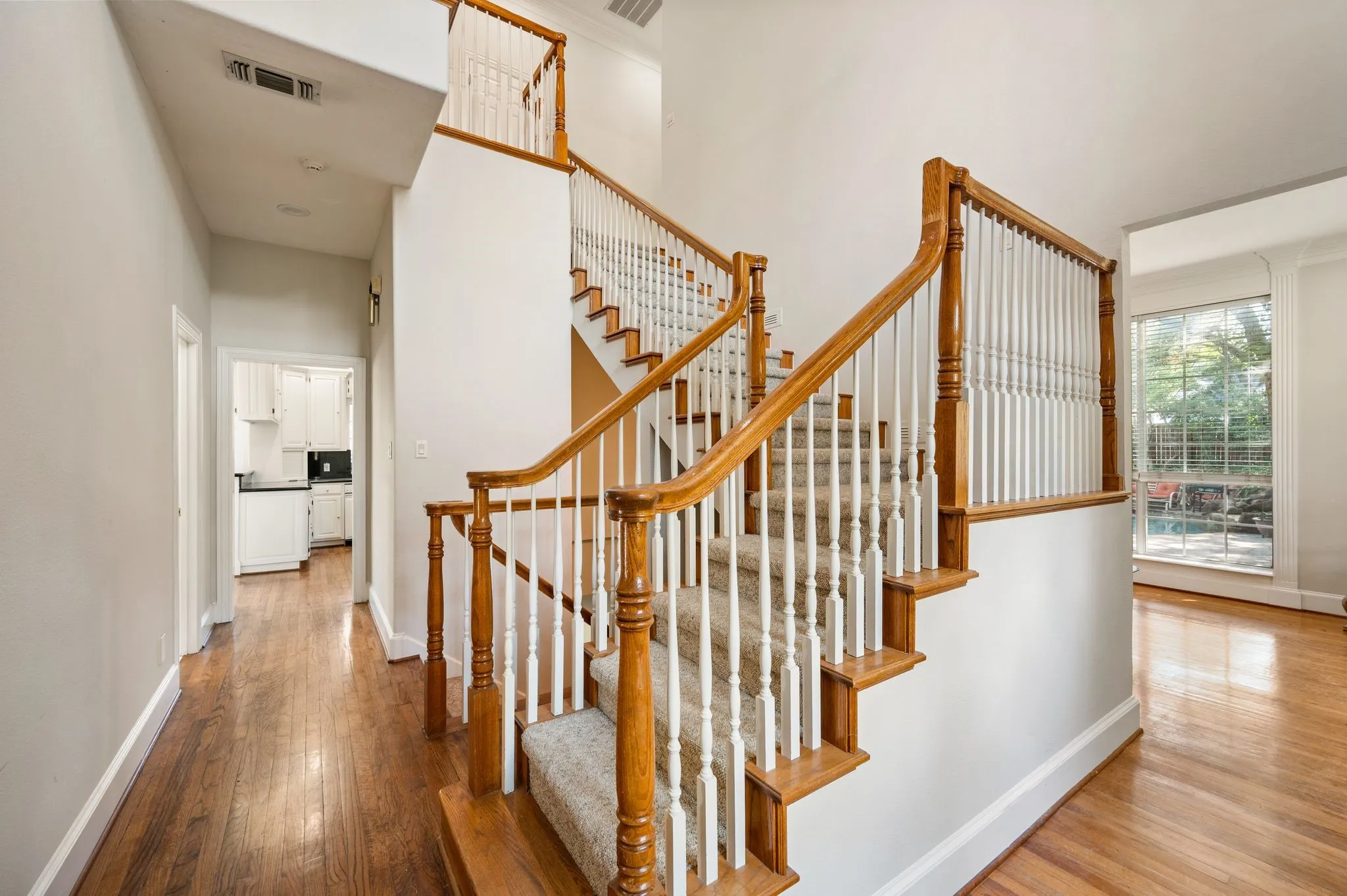 Grand staircase with wood handrails, white balusters, and carpeted treads