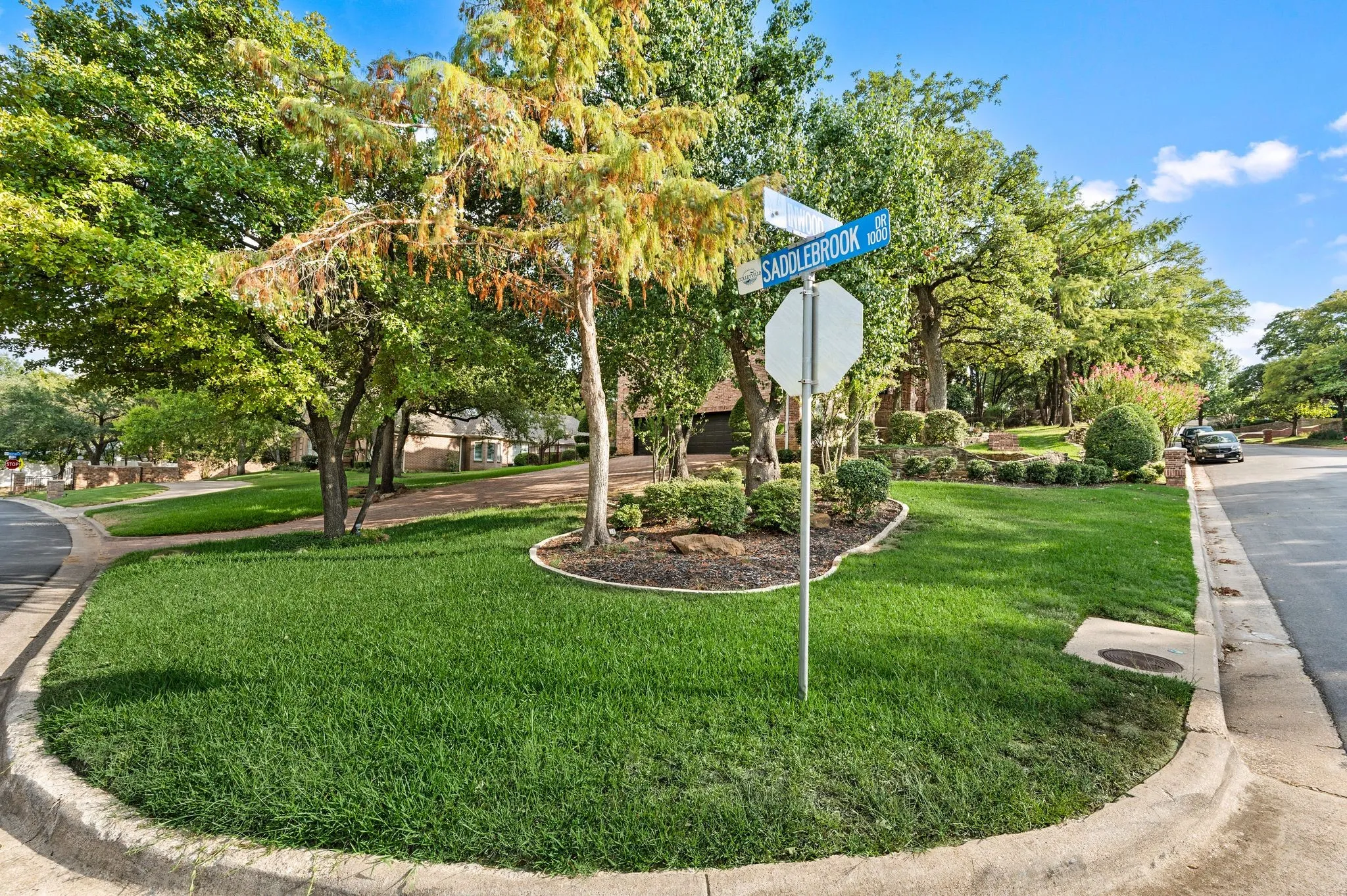 Manicured corner lot featuring mature trees and established landscaping