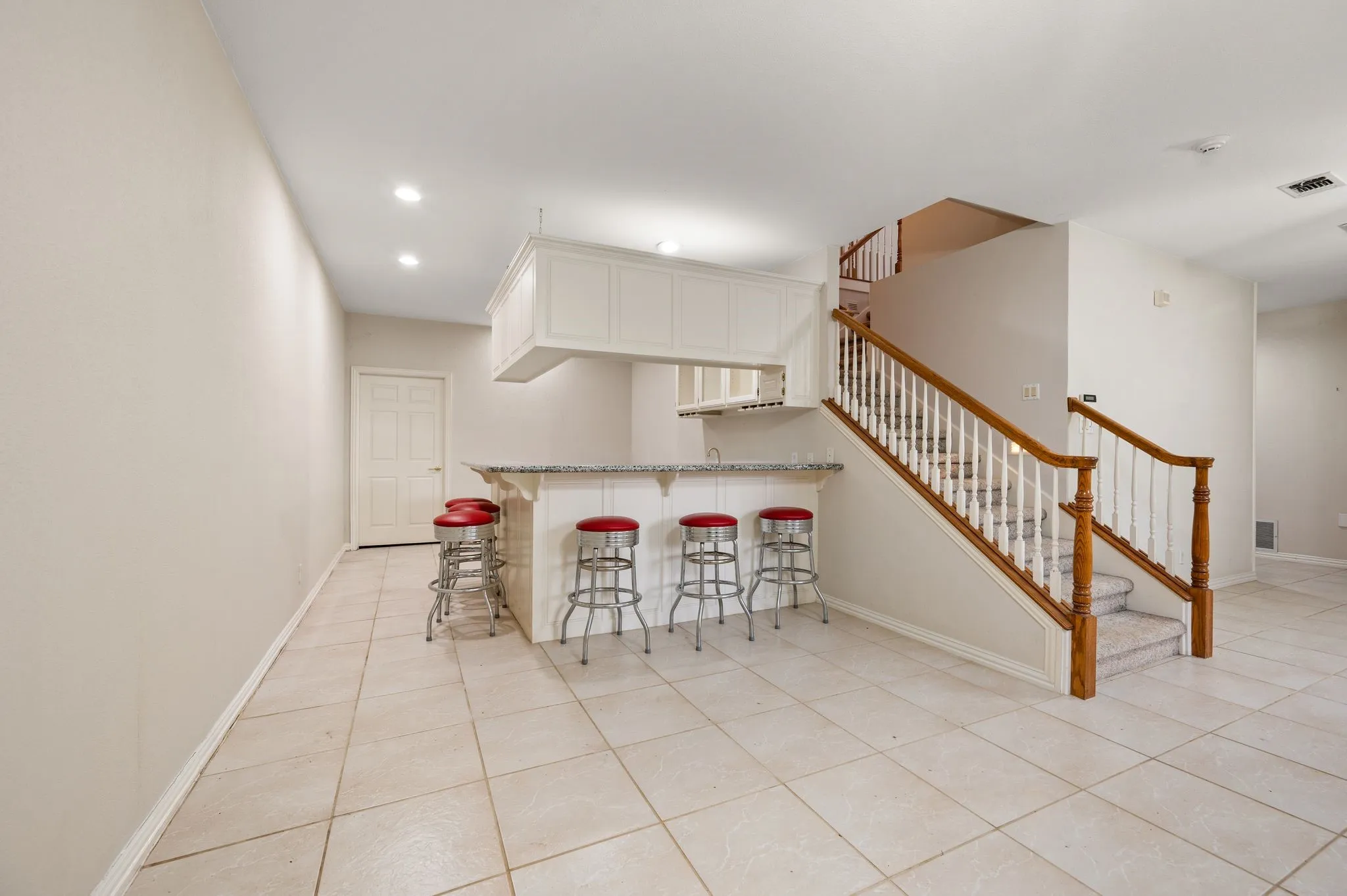 Tiled flooring throughout, built-in bar with white cabinetry, granite countertop, and integrated sink