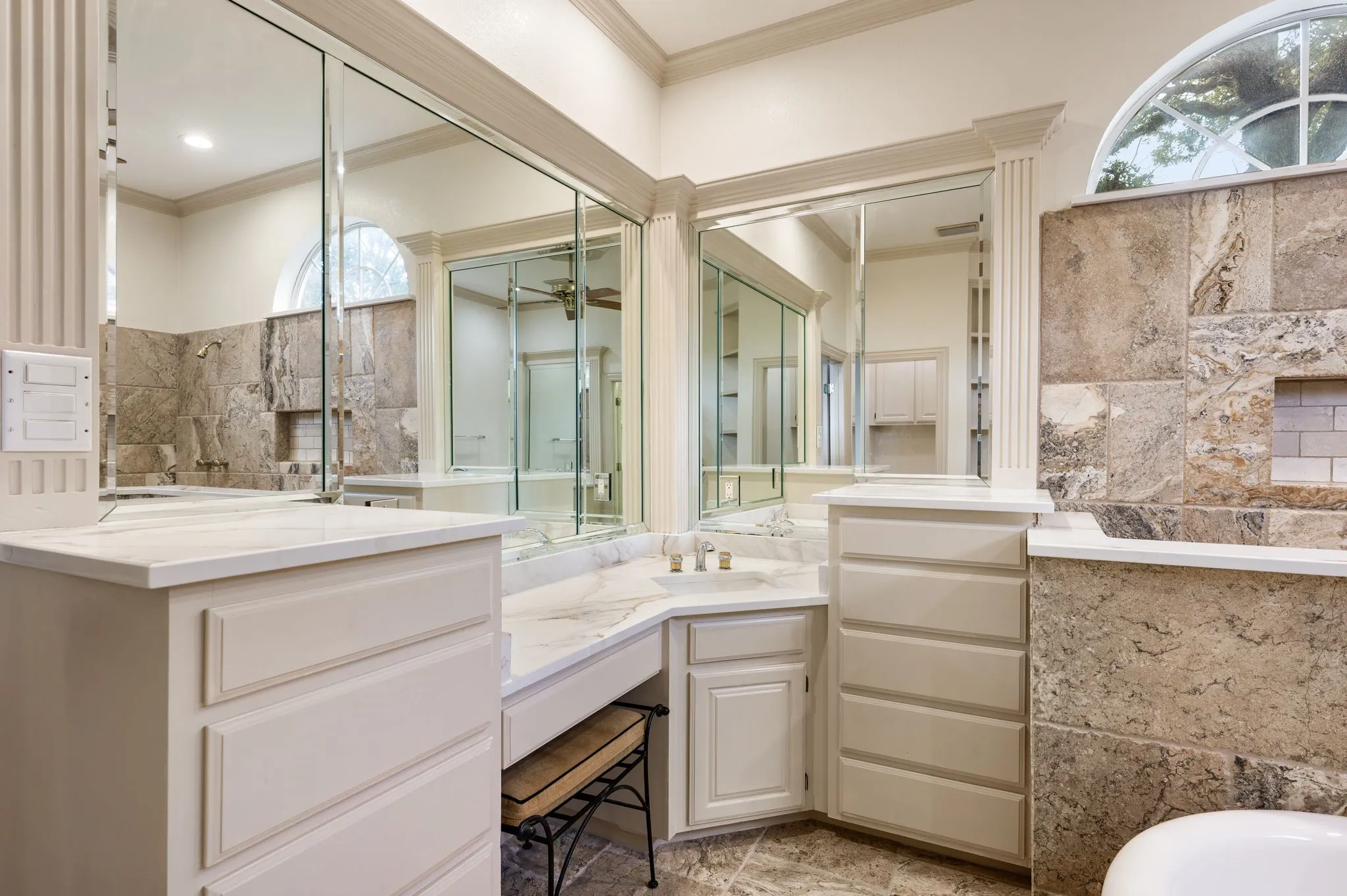Integrated vanity with dual sinks, built-in storage, arched window, and stone tile accents