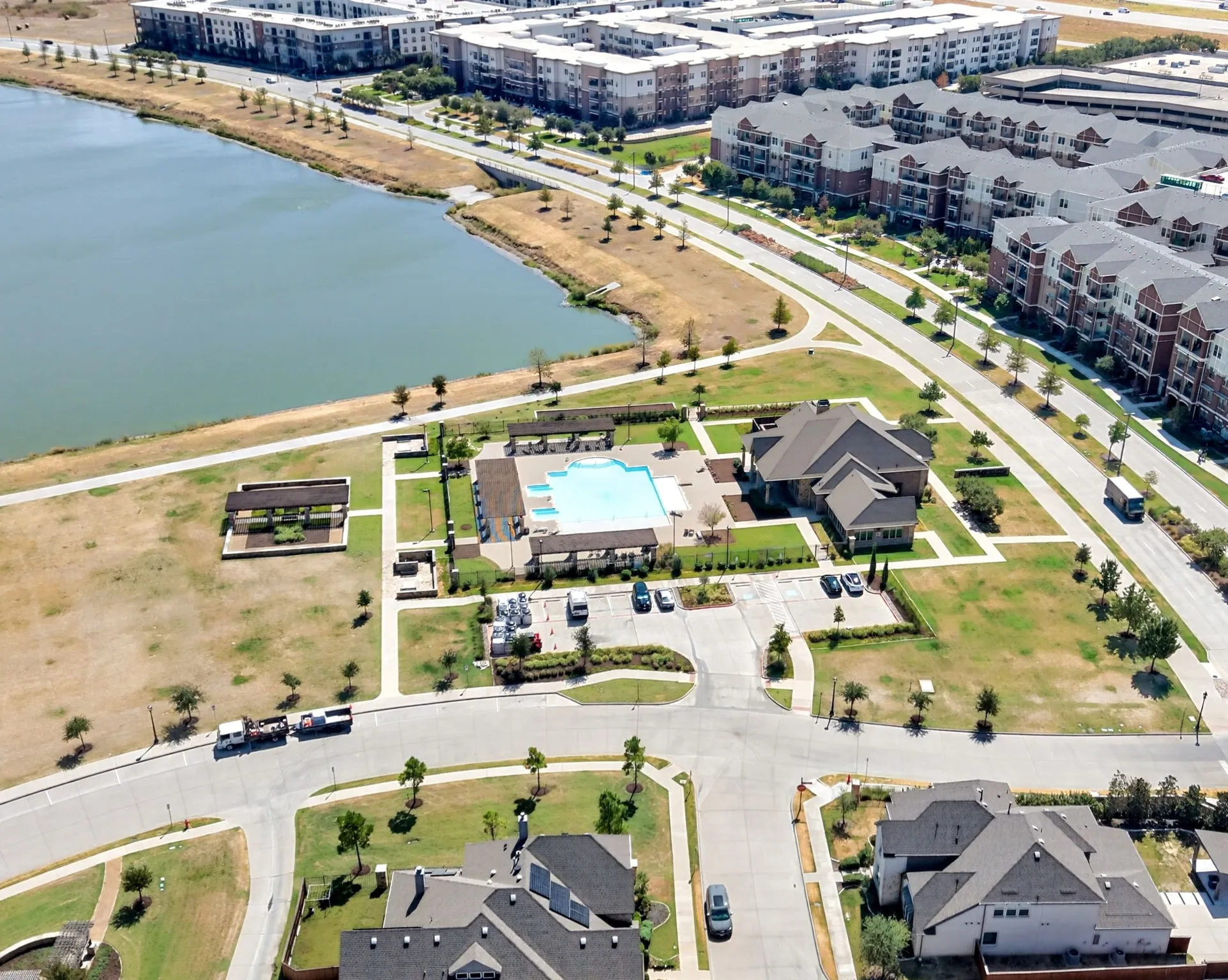 Aerial perspective highlighting a community with a large body of water, recreational building, outdoor swimming pool, and dedicated parking areas