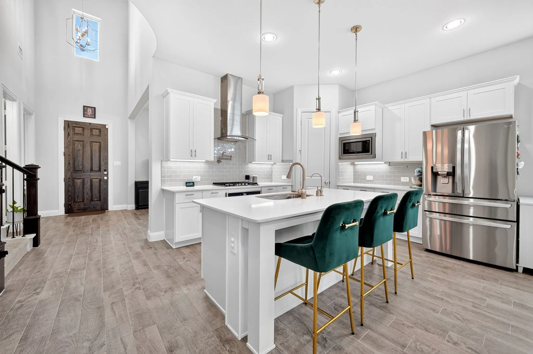 Gourmet kitchen with white cabinetry, stainless steel appliances, and a central island with a sink