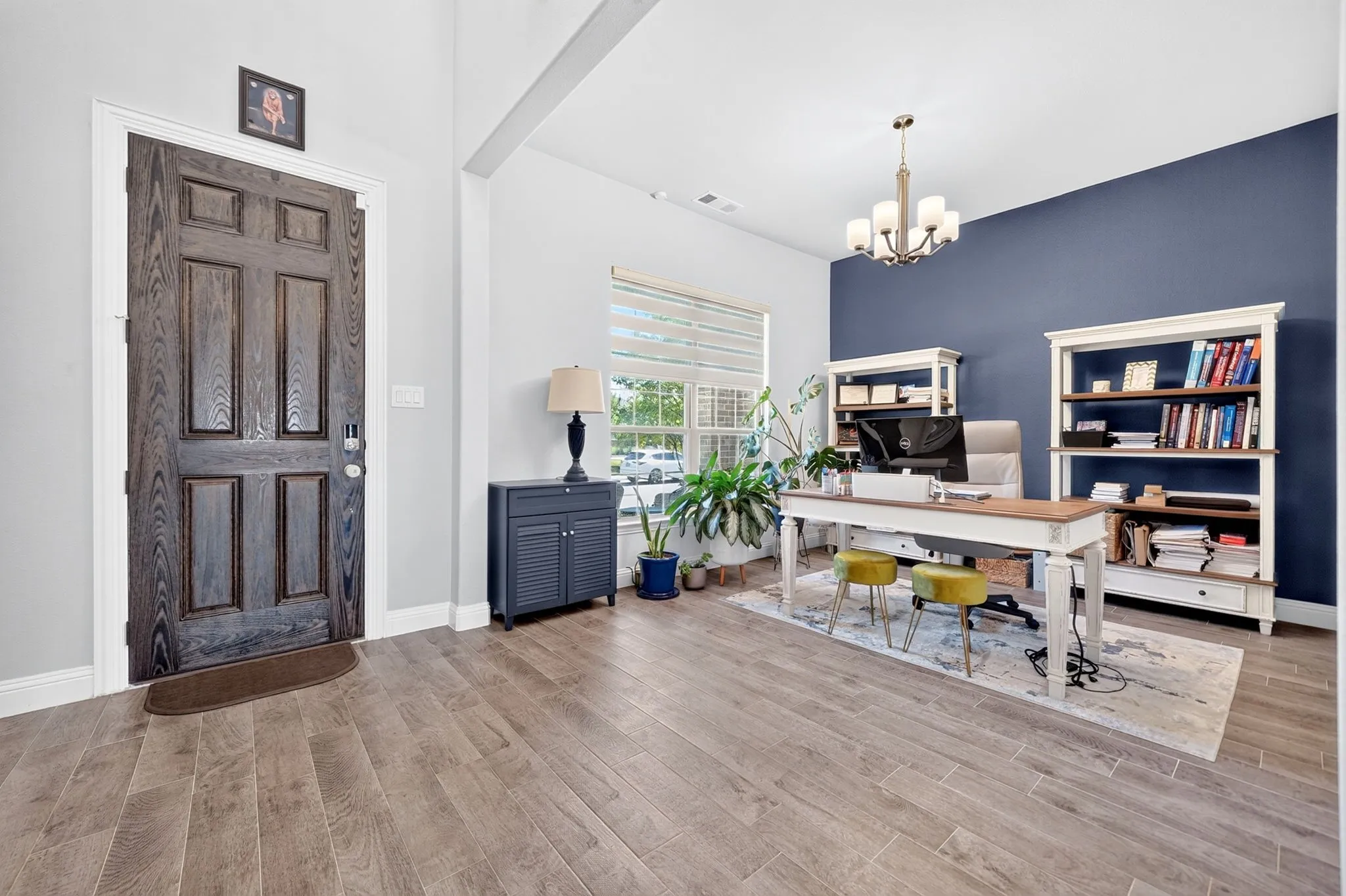 Entryway featuring wood-finish flooring, a paneled door, and a built-in chandelier