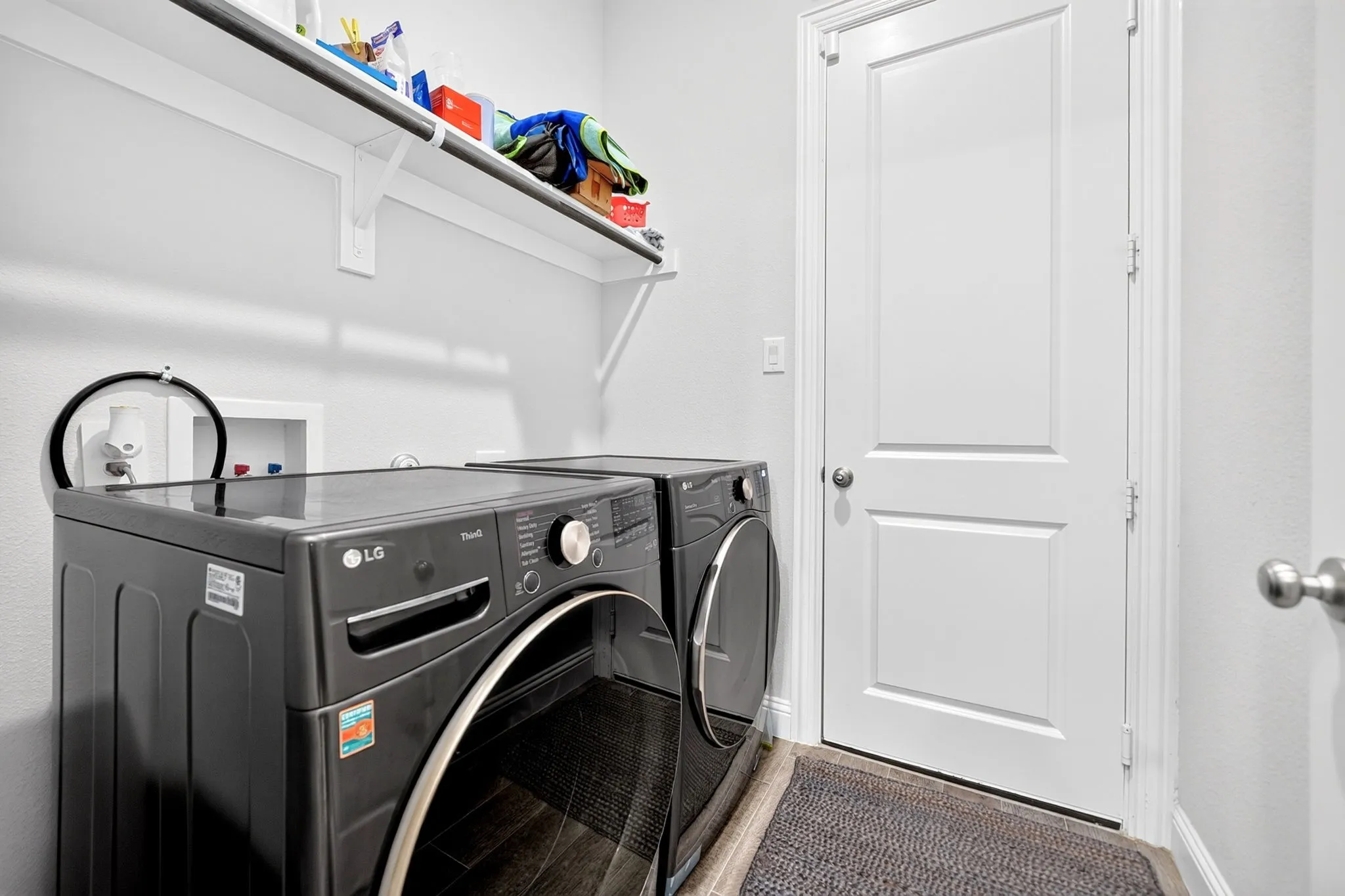 Laundry area featuring built-in shelving, wood-finish flooring, and a panel door