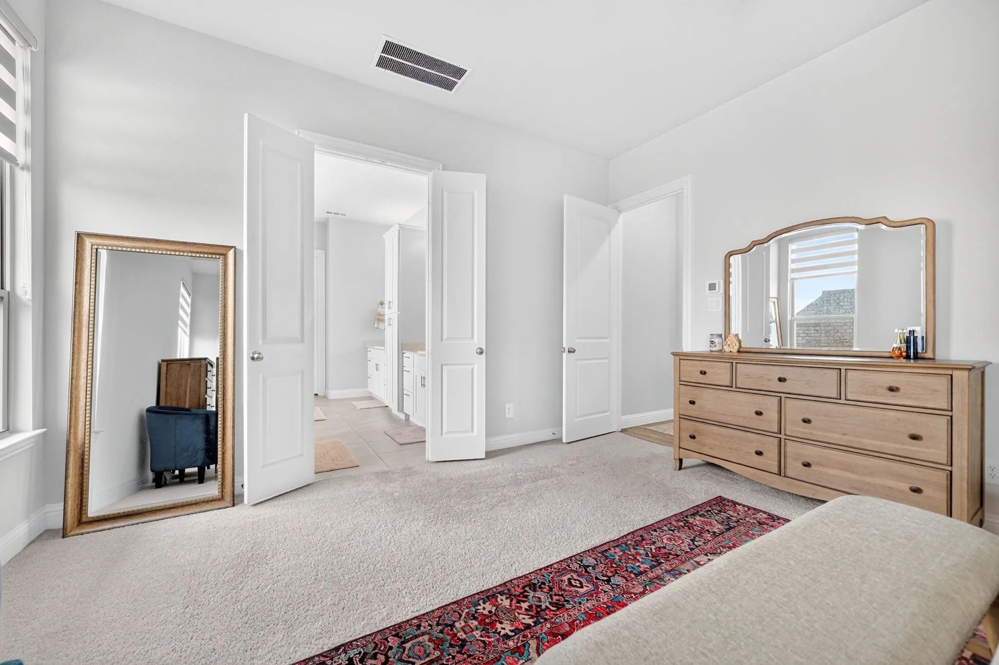 Plush carpeting, light-colored walls, and a doorway leading to an additional space with tile flooring